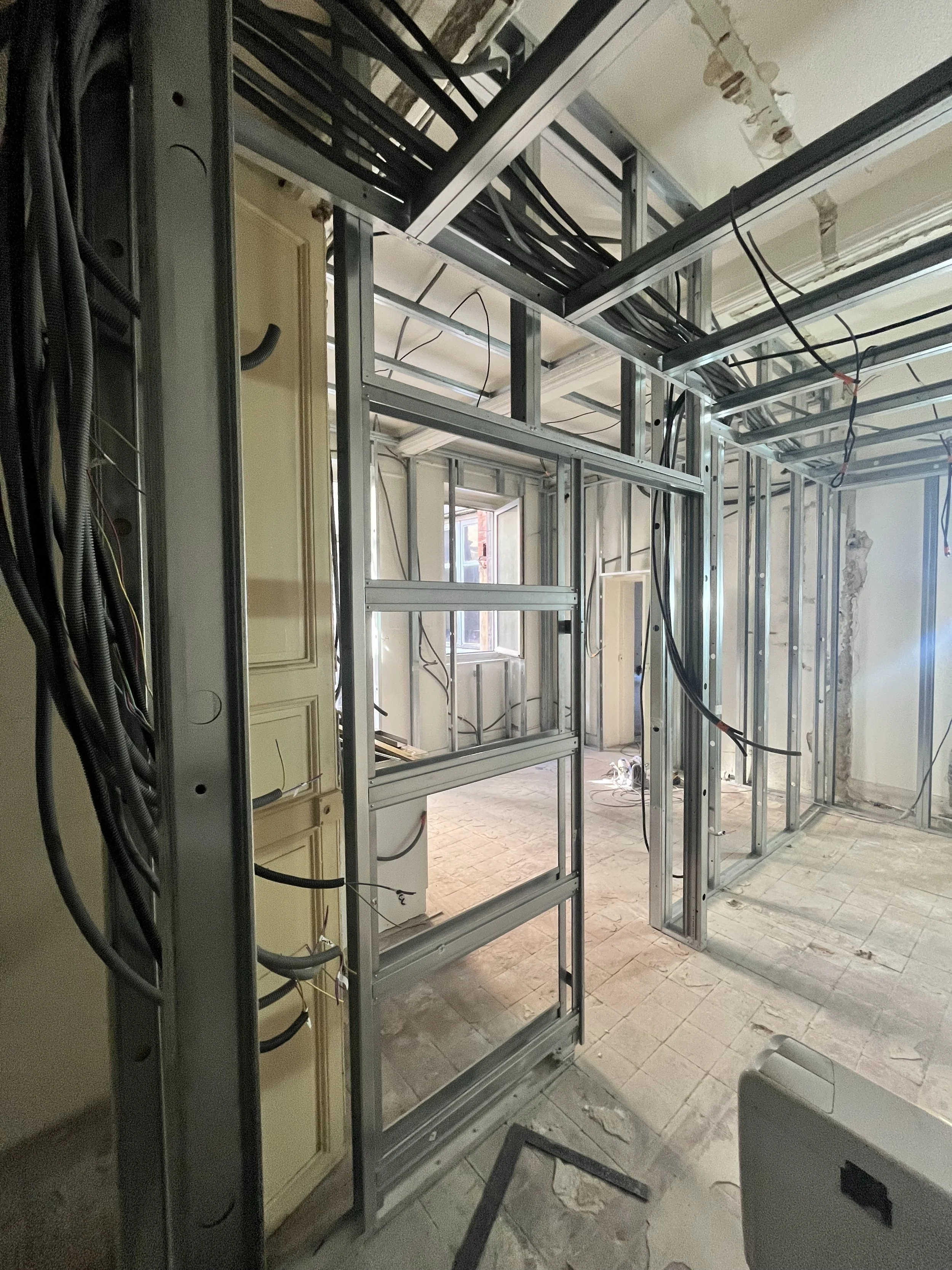 Travaux de construction intérieure avec structure en métal, câbles électriques et murs en cours de rénovation.