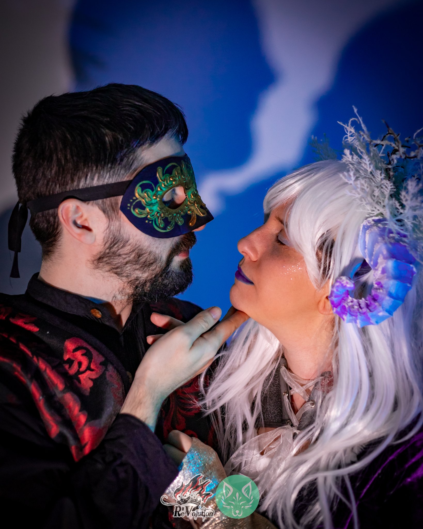 Una pareja con disfraces de Carnaval, él con máscara y ella con peluca blanca y accesorios de fantasía, rol en vivo la corte del rey cisne