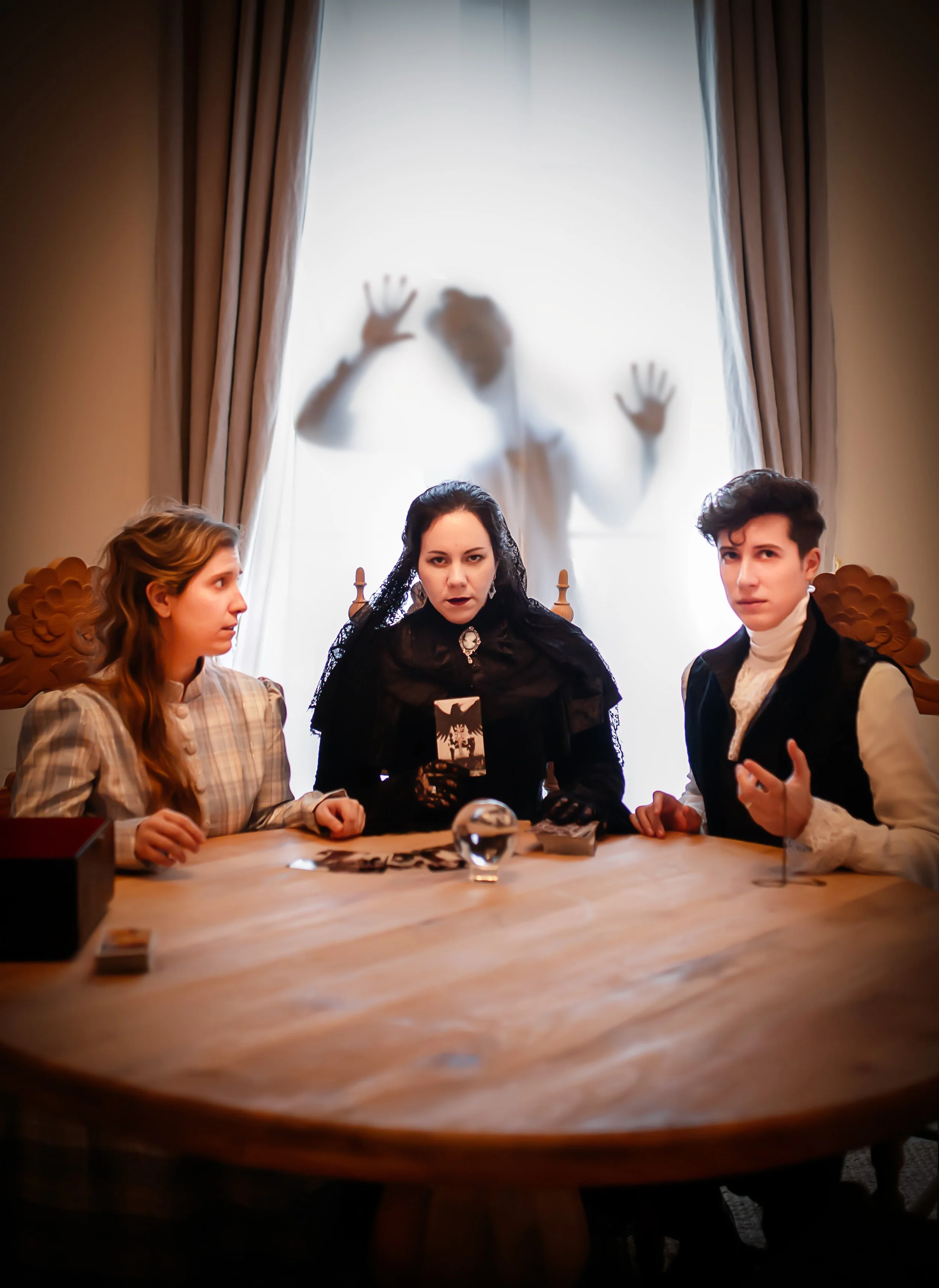 Tres personas sentadas en una mesa, con una figura difusa y fantasmal | ReVolution | Rol en Vivo España