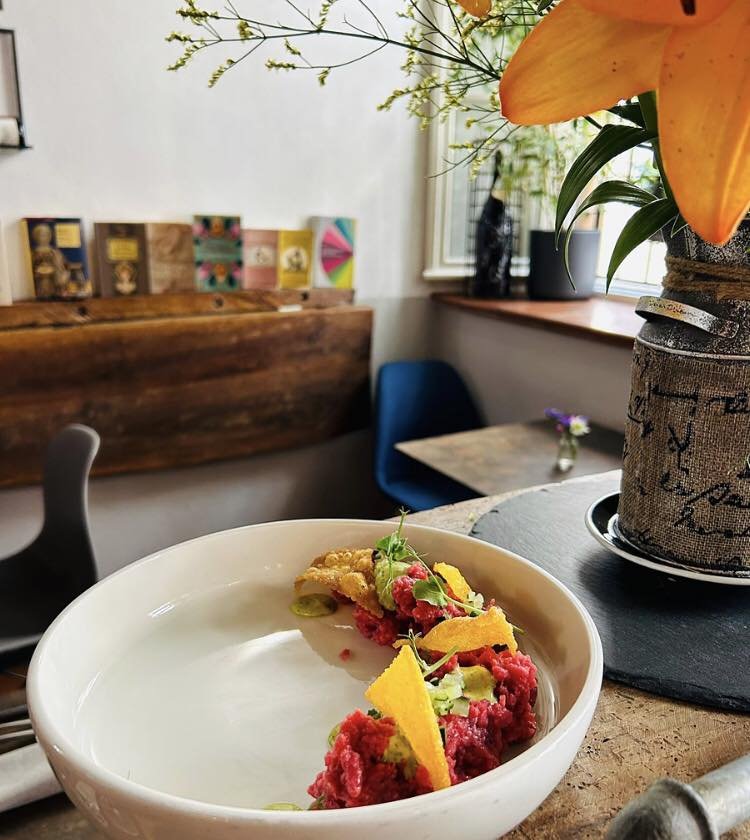 Piatto di tartare di carne in un ristorante accogliente con decorazioni floreali.