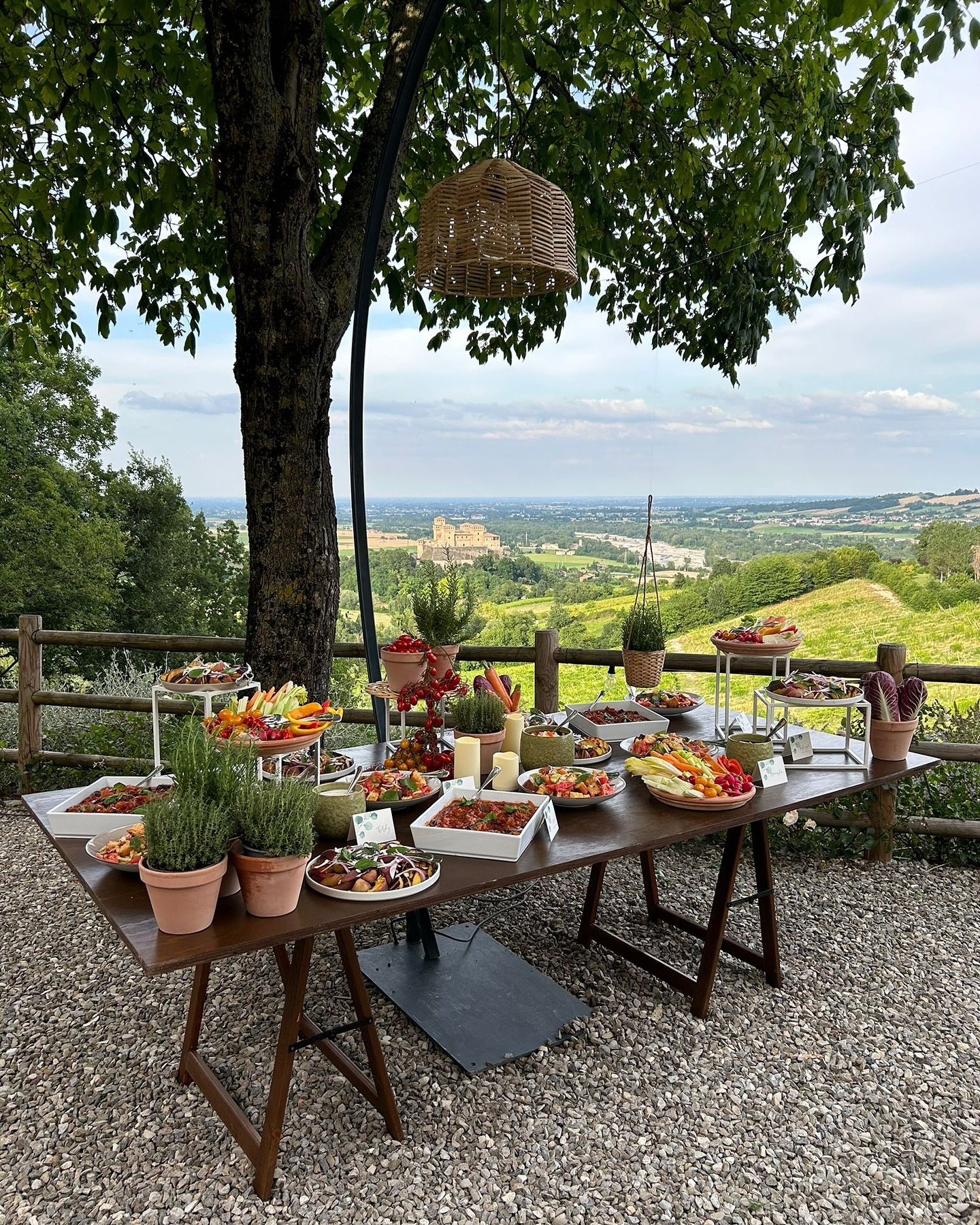 Tavolo all'aperto con cibo, terrazzamenti e vista panoramica in campagna italiana.