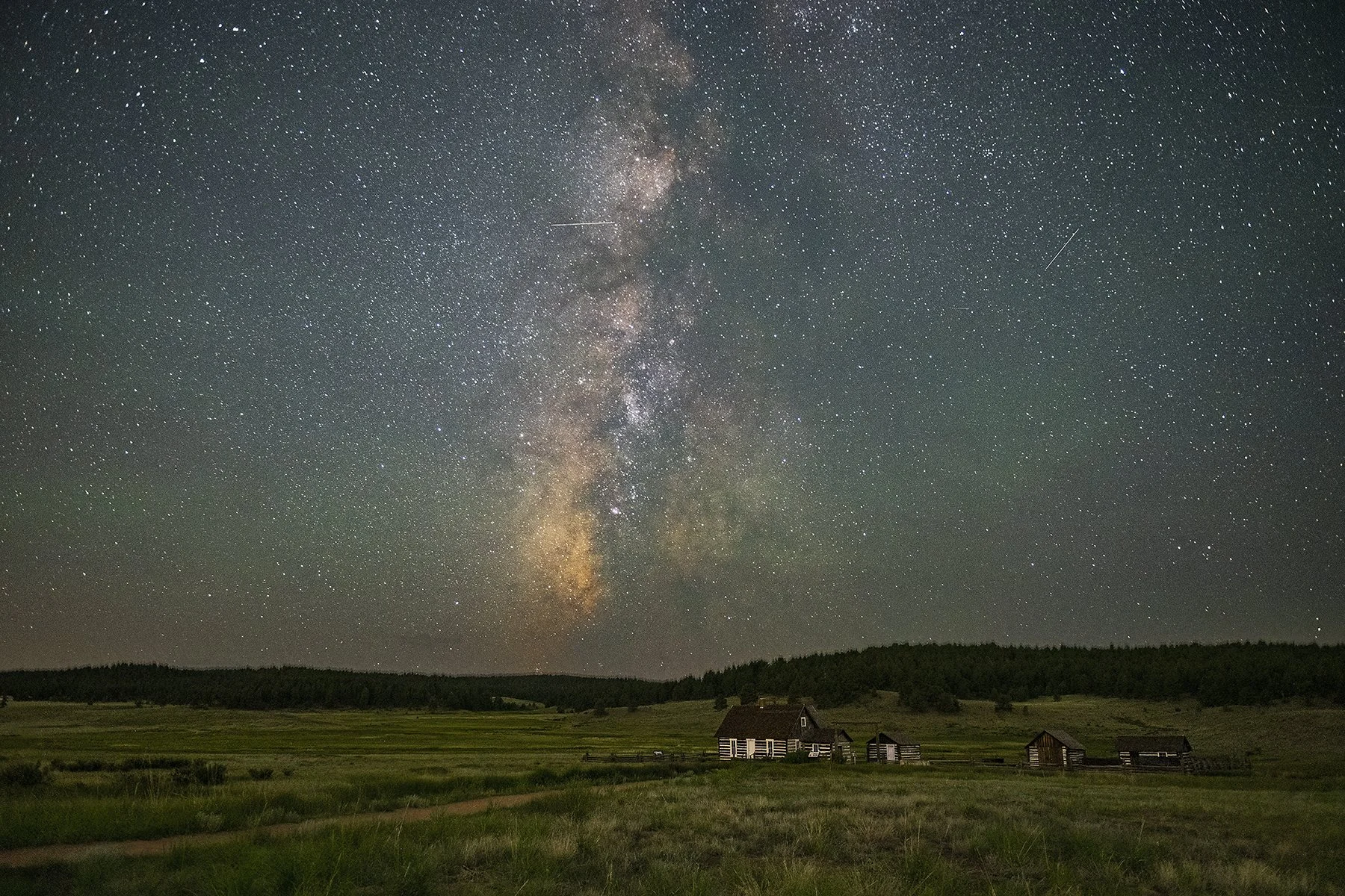 The historic homestead at Florissant Fossil Beds National Monument appears small in comparison to the Milky Way in the sky above.