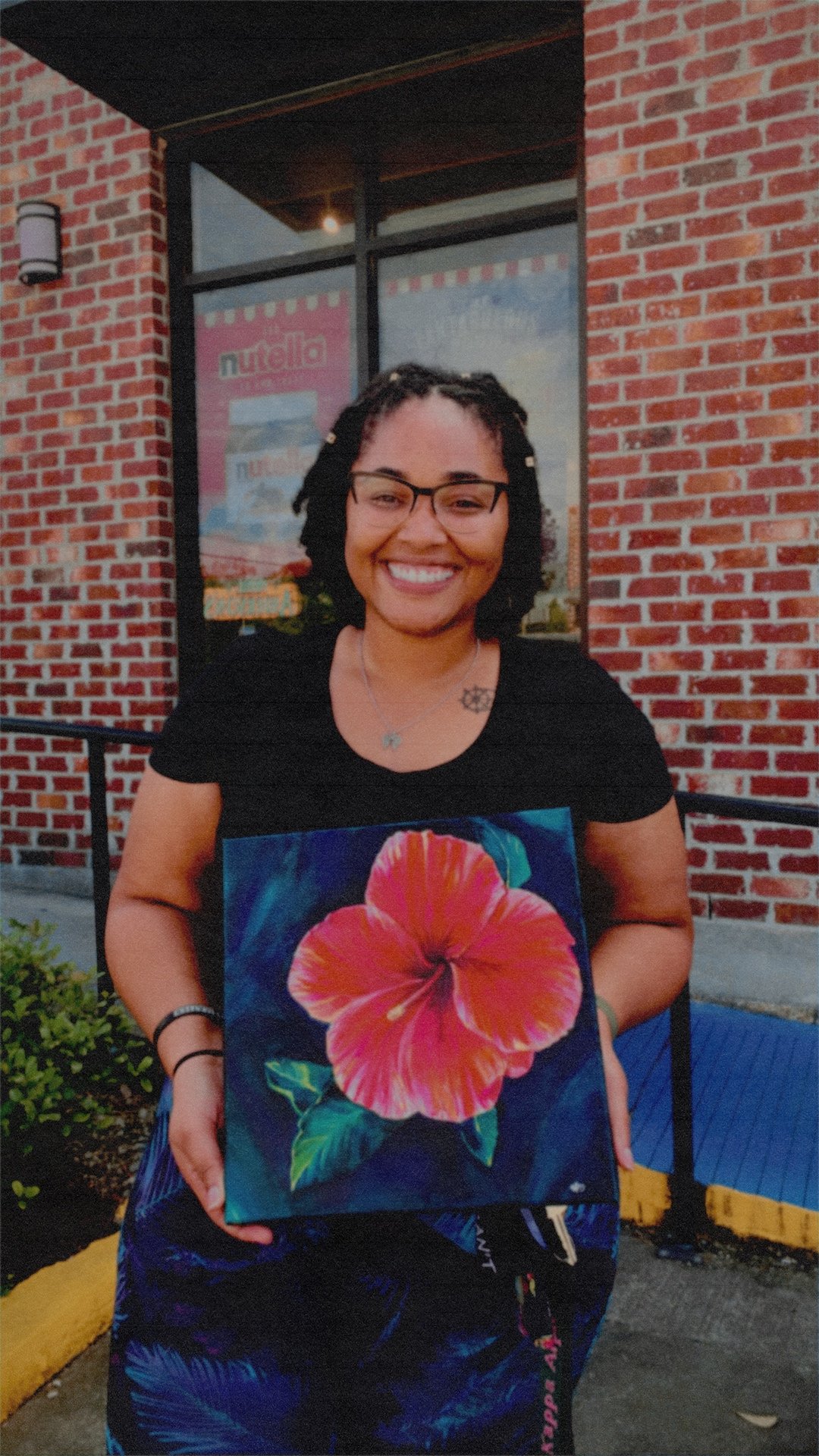 Woman holding a painting of a hibiscus flower