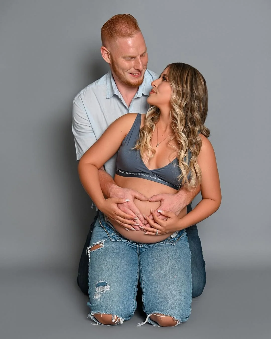 Expecting couple posing together during a studio maternity photoshoot at 11th Hour Studios.