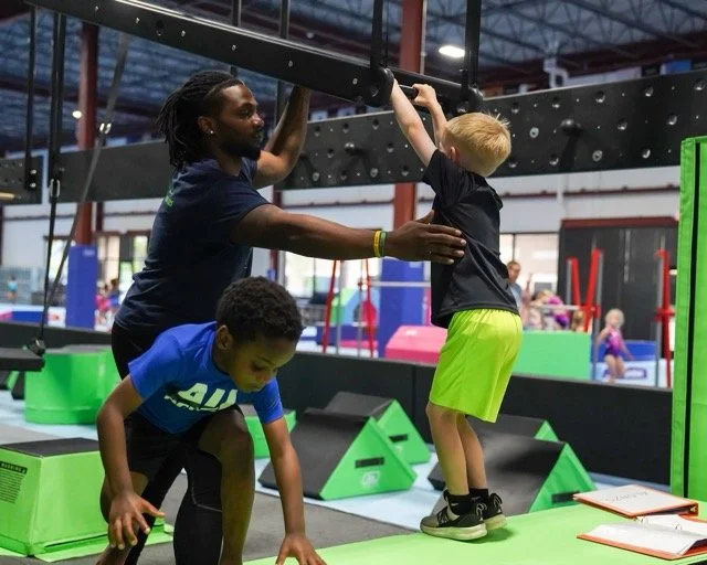 coach helping little boy ninja course