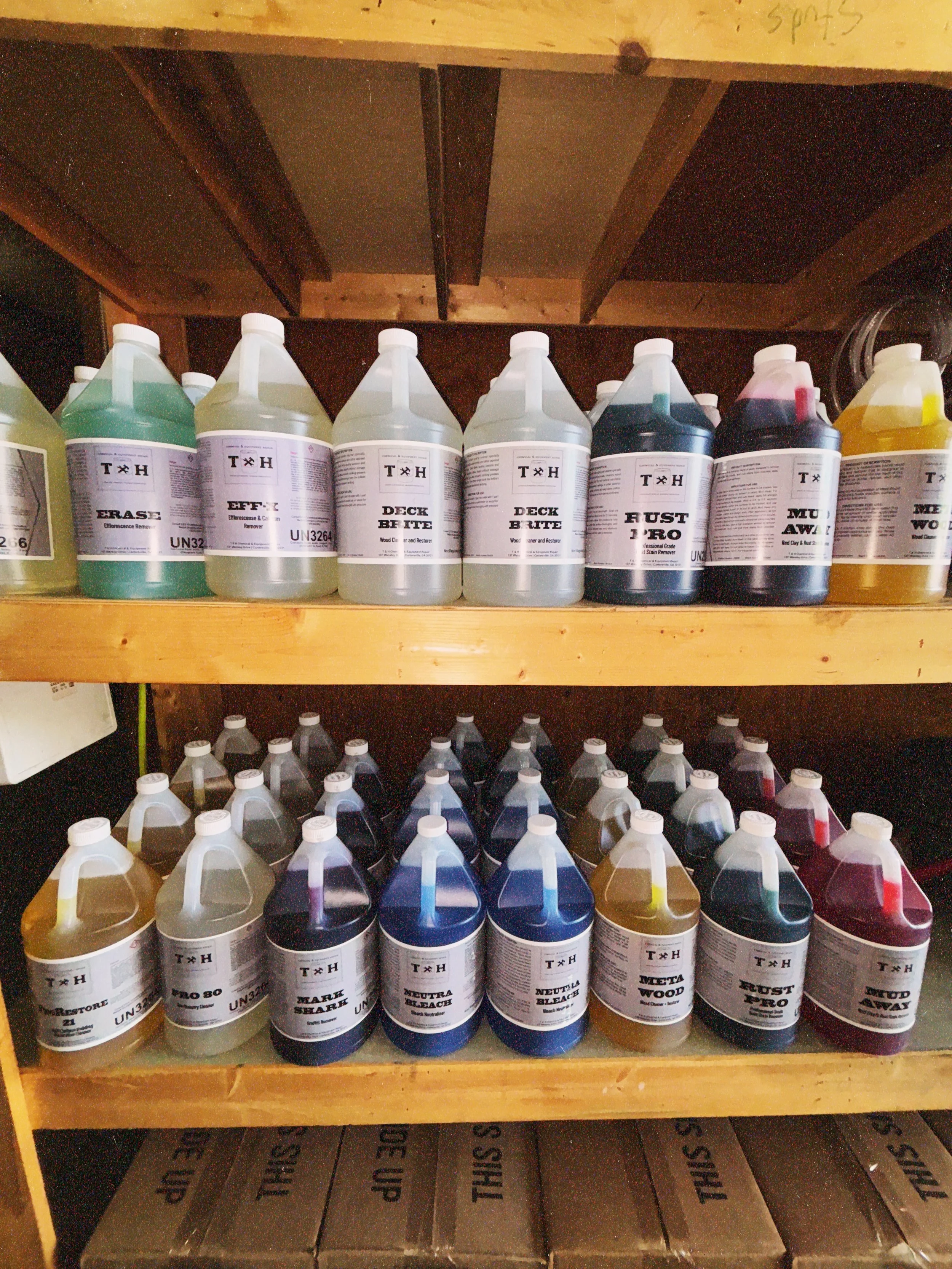 Shelf with various bottles of wood and metal restoration and stain removal chemicals, labeled with different usage instructions and color codes.