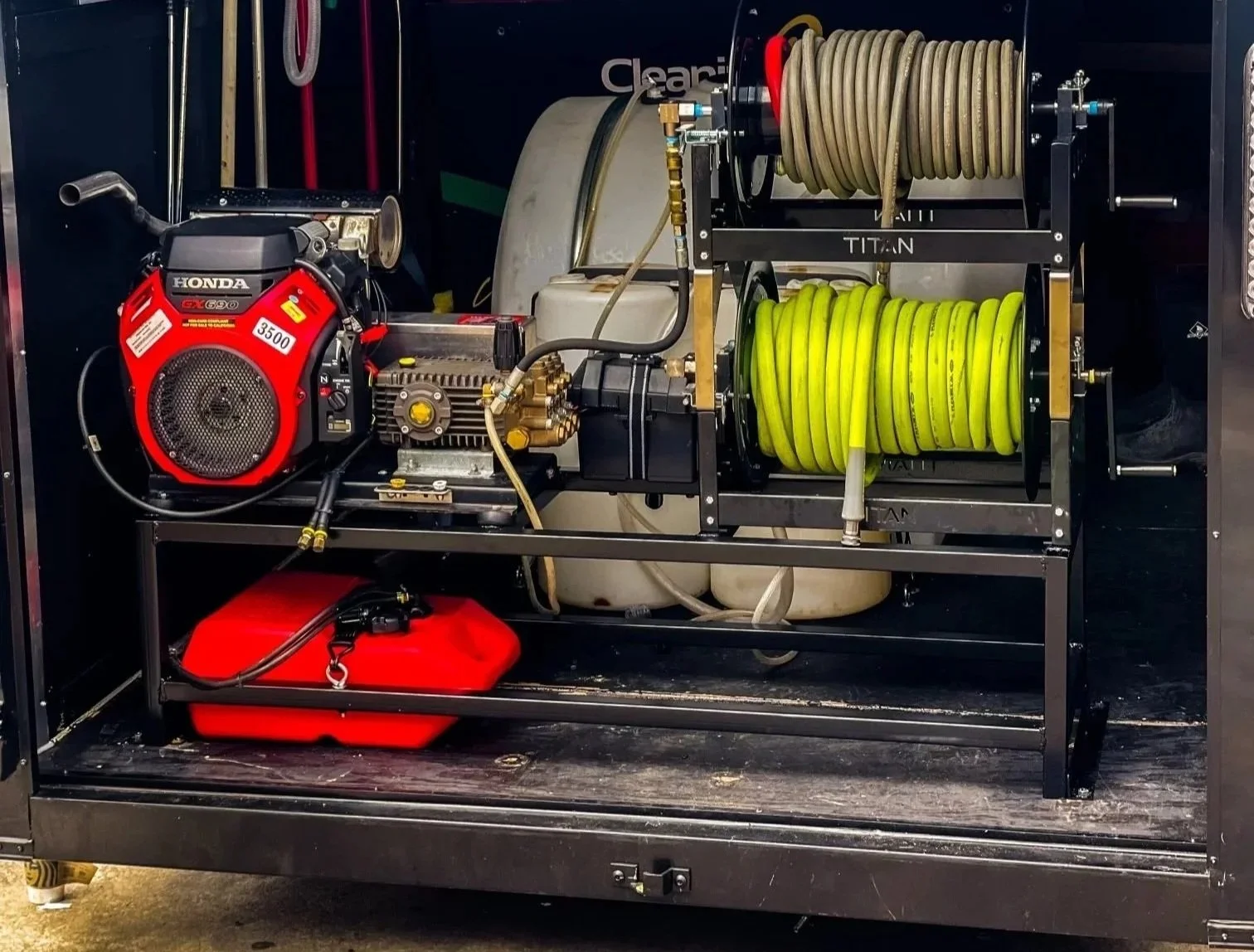 A portable fire-fighting pump with yellow and gray hoses, a Honda engine, and a fuel container.