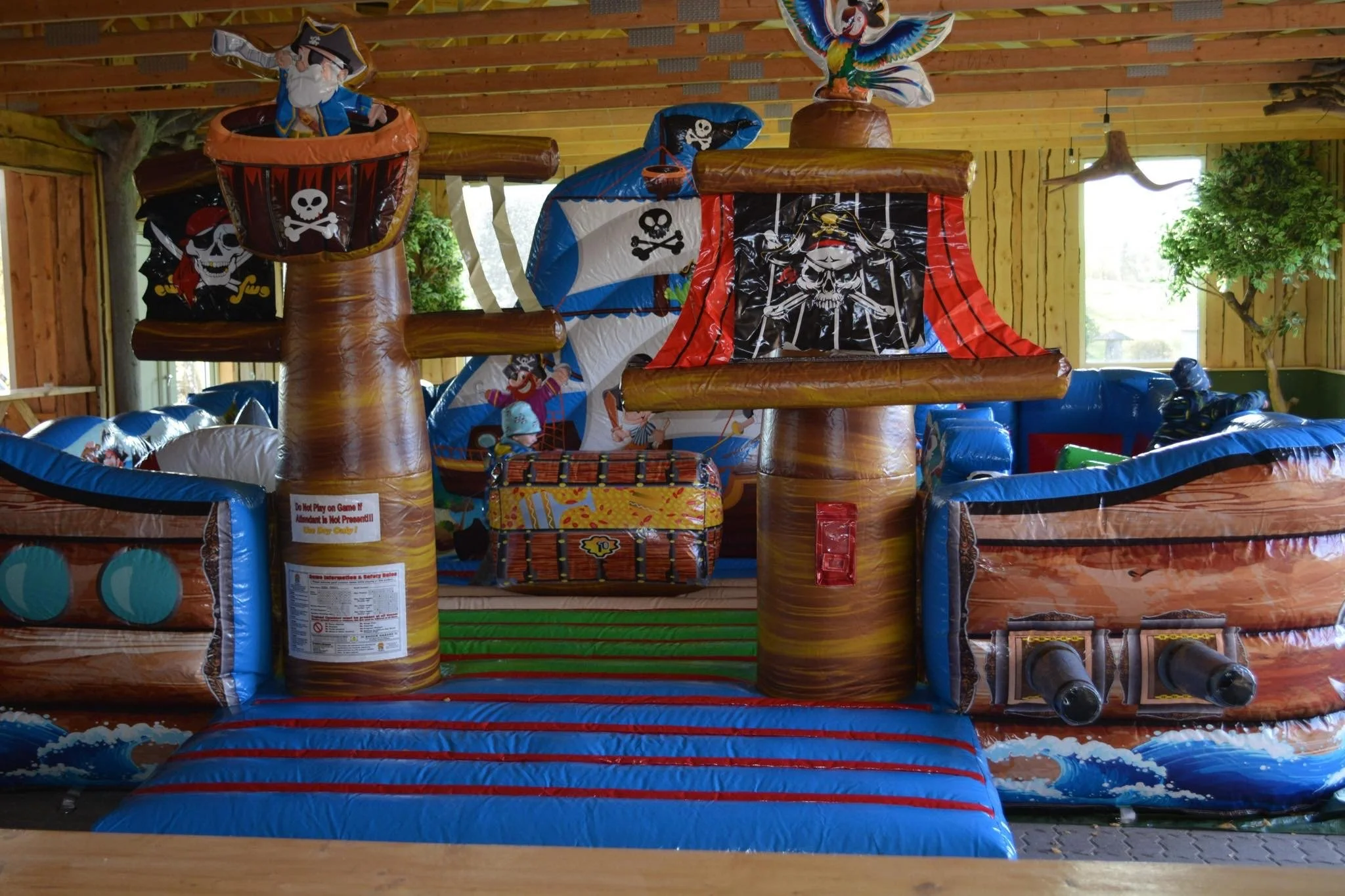 Inflatable pirate-themed bounce house with pirate ship design, skull and crossbones flags, and pirate characters inside.