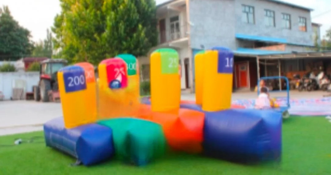 Colorful inflatable bounce house with numbered pillars on a grassy area outside a building.
