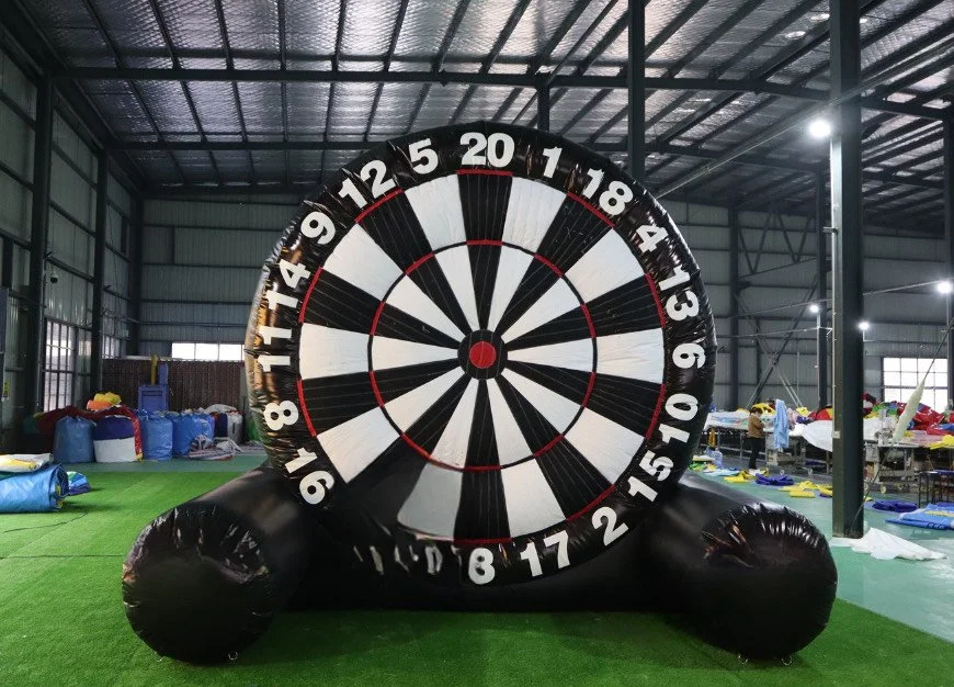 Inflatable dartboard with numbers from 1 to 20 in a warehouse with inflatable toys and equipment in the background.