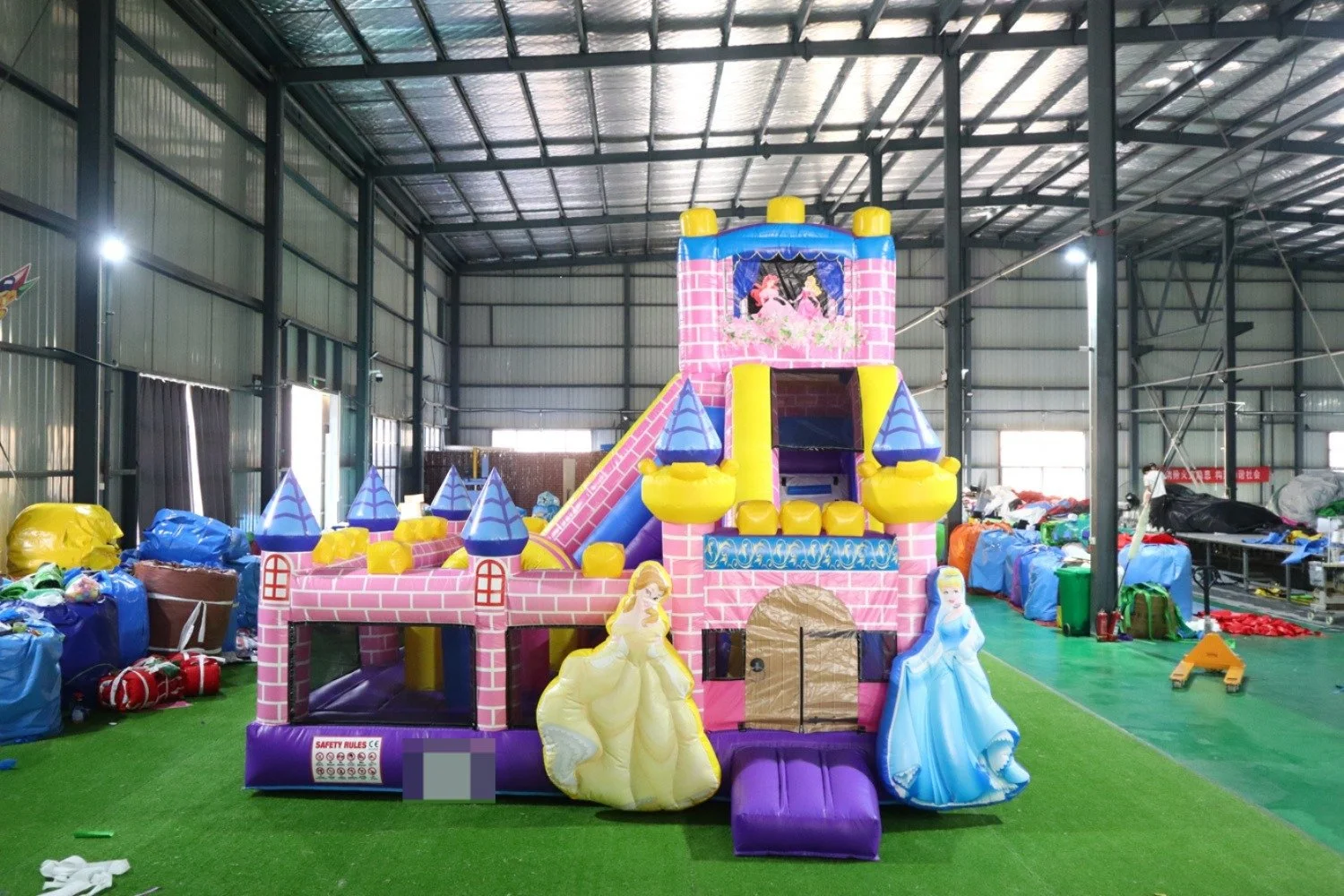 Colorful inflatable castle with princess theme in an indoor warehouse space.