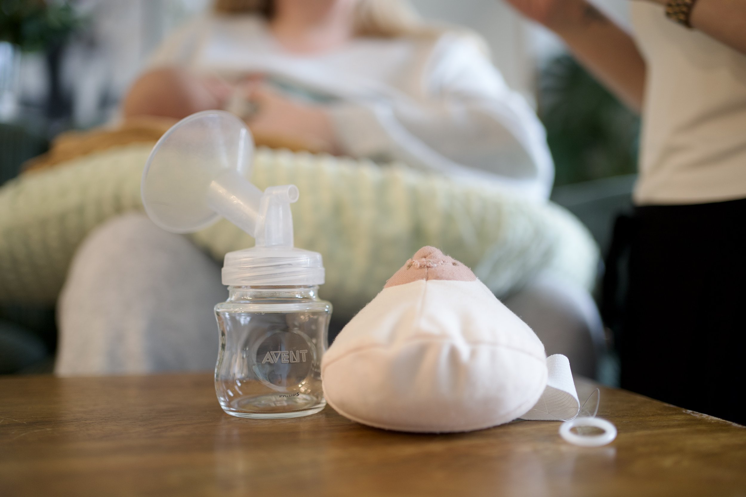 Woman holding a newborn baby close to her chest while sitting on a couch.