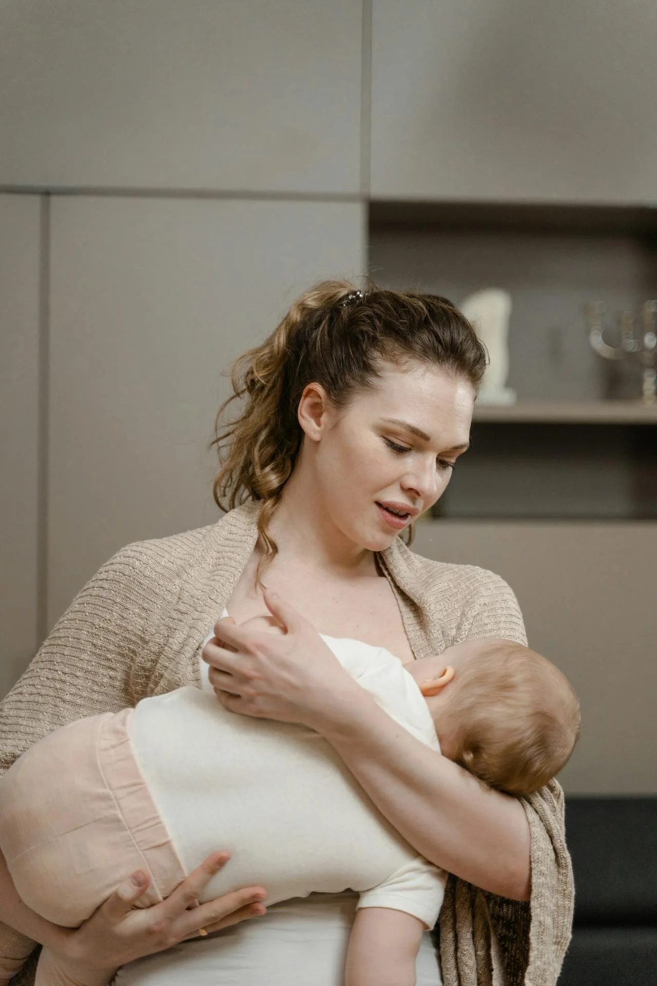 A woman breastfeeding a young child in a cozy indoor setting.