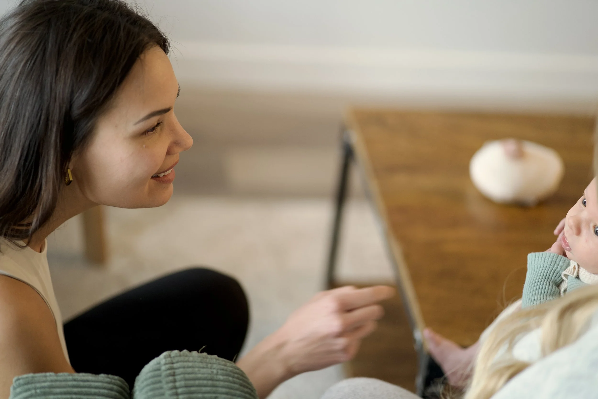A cozy bedroom corner with a white nightstand holding candles, a bottle, and framed art, next to a bed with striped bedding and textured pillows.
