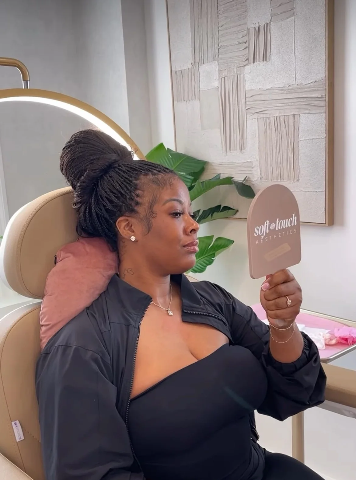 Patient reviewing her lip filler results in a handheld mirror after a cosmetic aesthetic treatment in a luxury medical spa.