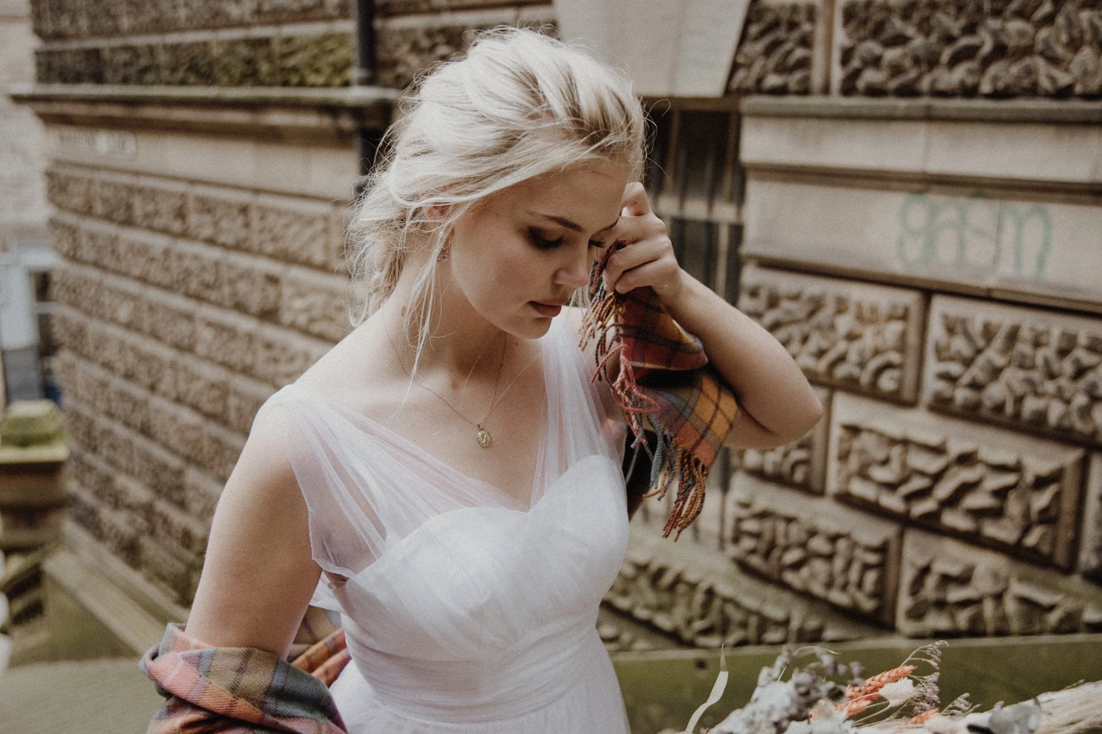  bridal photo portrait of blonde model walking in edinburgh old town Royal Mile with a bouquet of dried flowers in arm and edinburgh old town in the background 