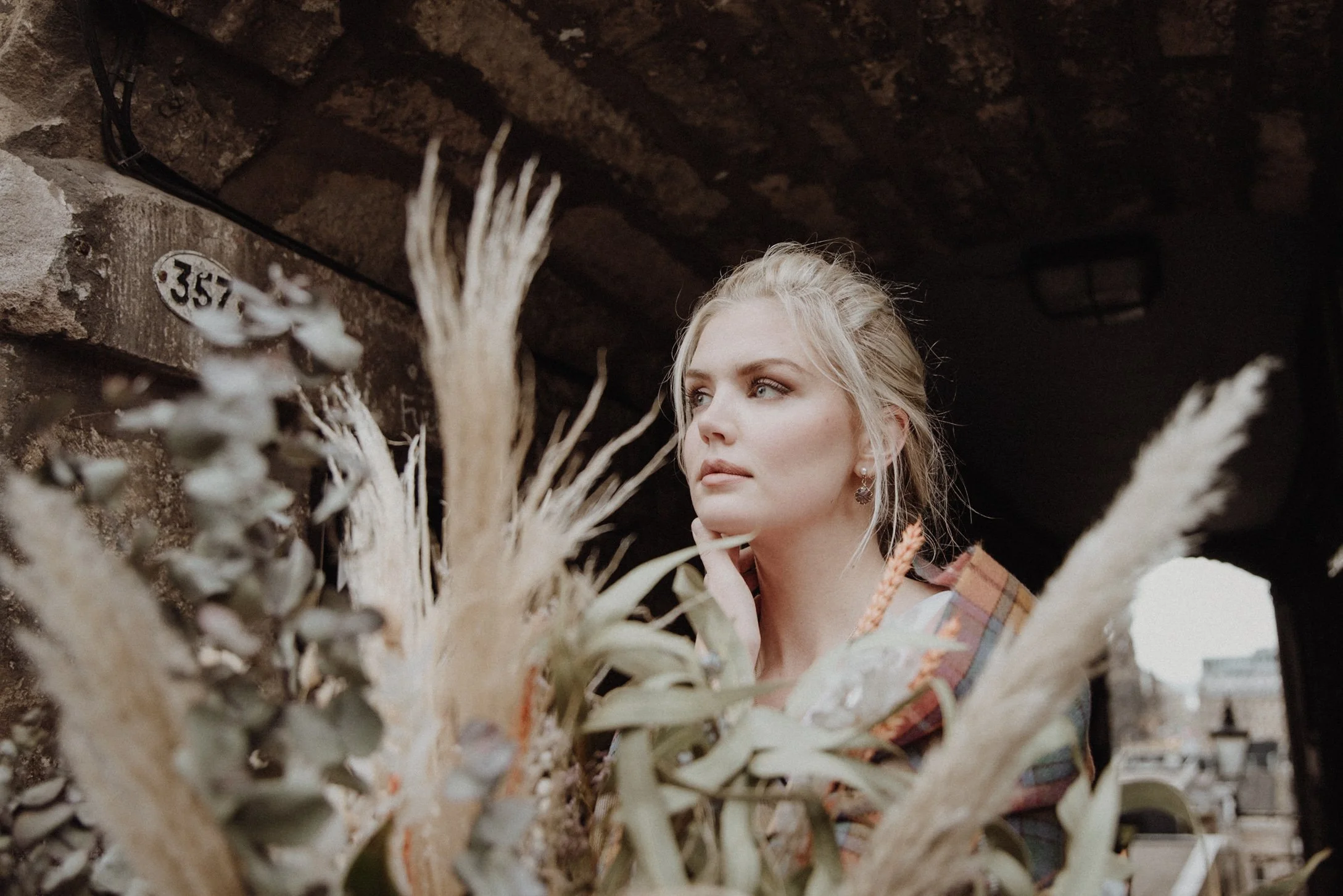  bridal photo portrait of blonde model walking in edinburgh old town Royal Mile with a bouquet of dried flowers in arm and edinburgh old town in the background 