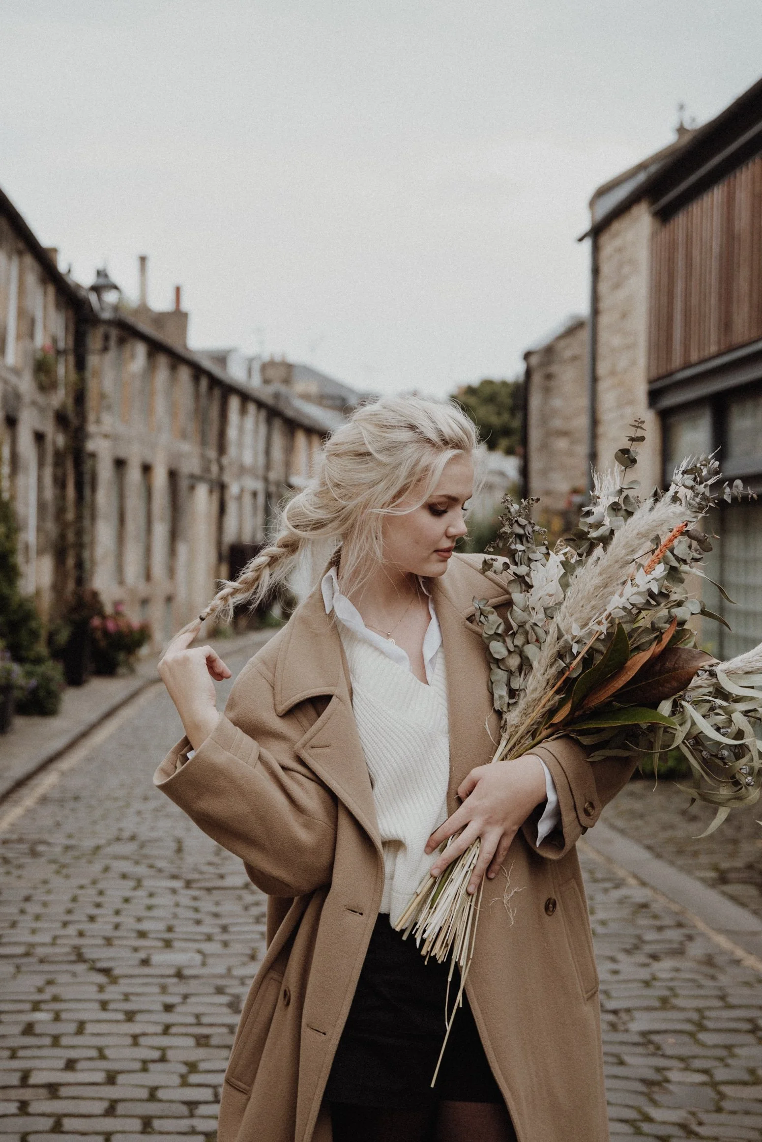  photo portrait of blonde model walking in edinburgh new town Circus Lane with a light camel coat and a bouquet of dried flowers in arm 