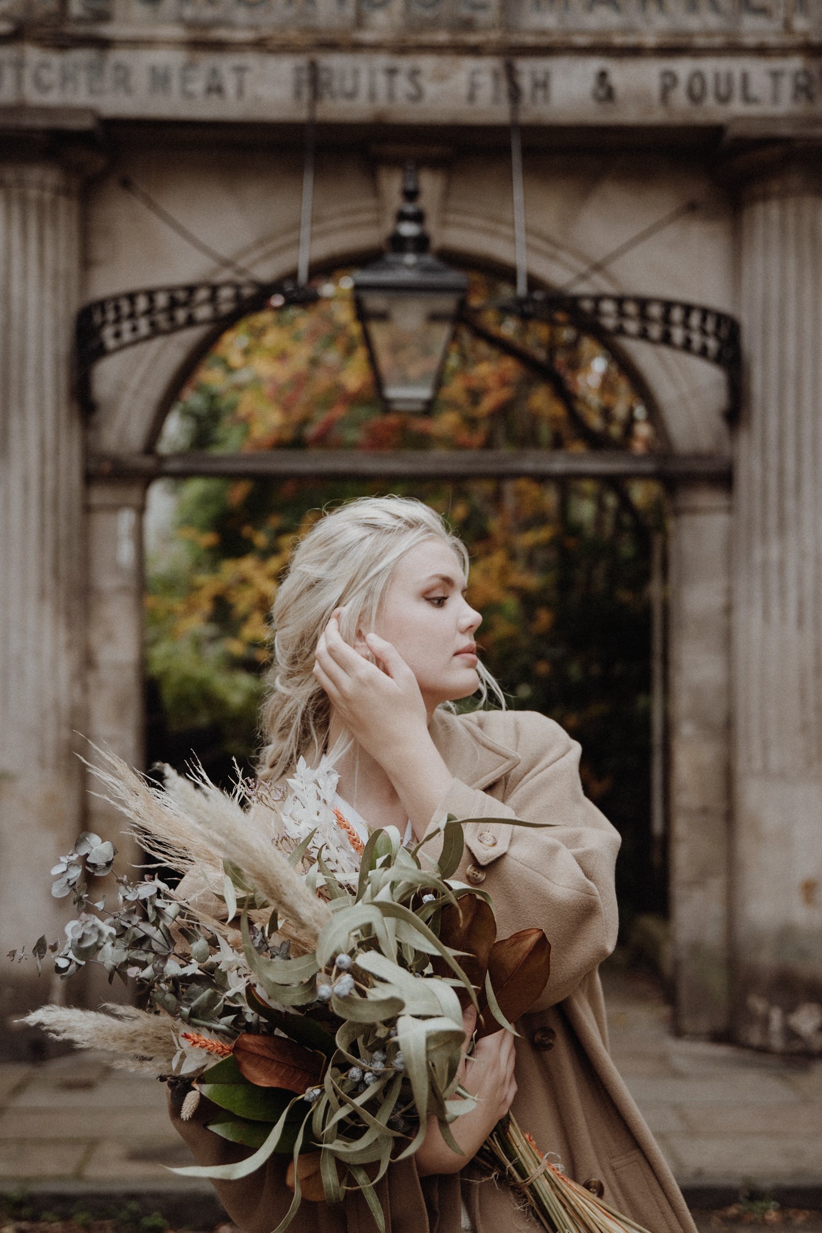  photo portrait of blonde model walking in edinburgh new town Stockbridge with a light camel coat and a bouquet of dried flowers in arm 