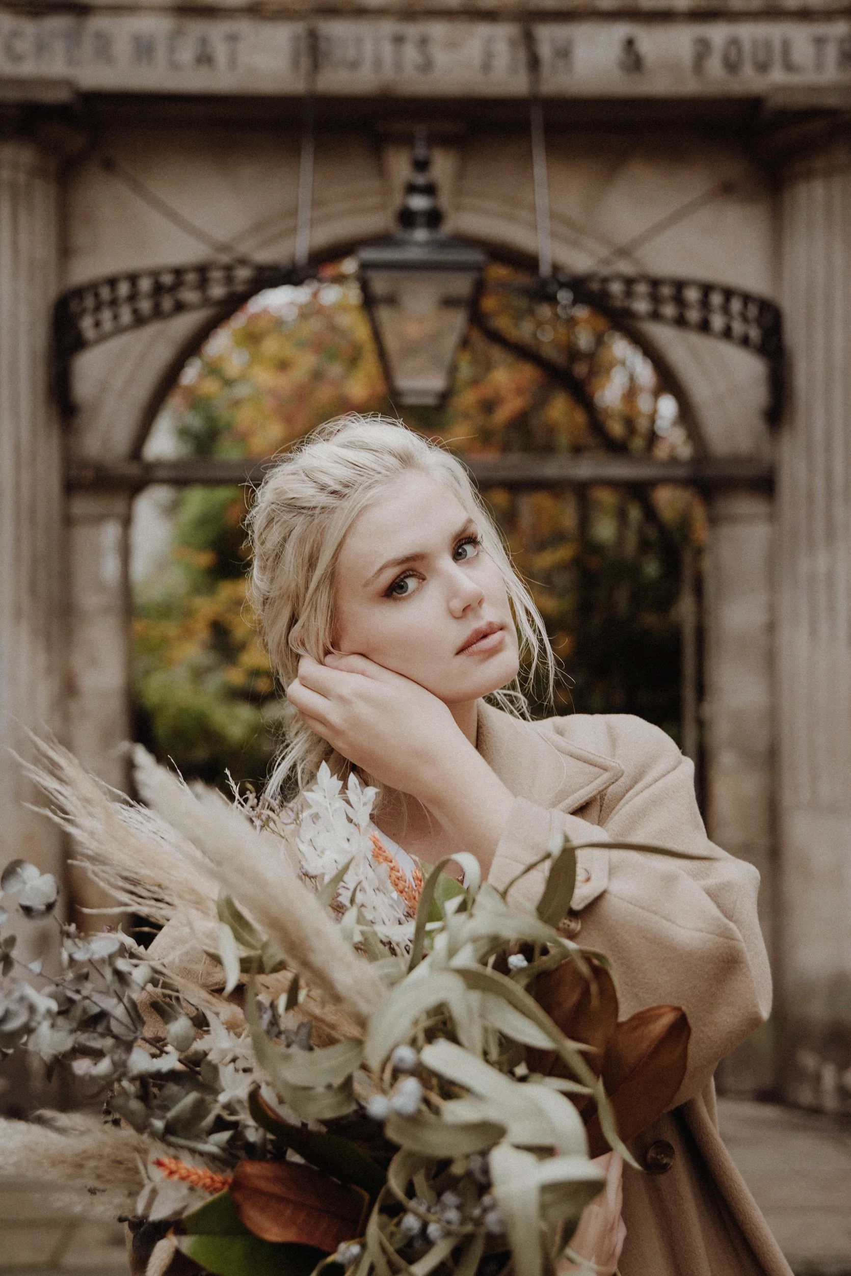  photo portrait of blonde model walking in edinburgh new town Stockbridge with a light camel coat and a bouquet of dried flowers in arm 