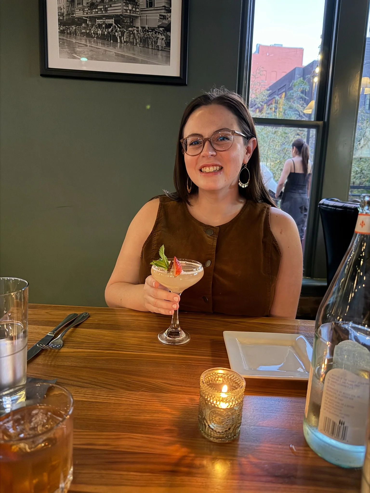 A therapist in her thirties enjoying a quiet moment at a restaurant, representing reflection, balance, and life outside of clinical work.