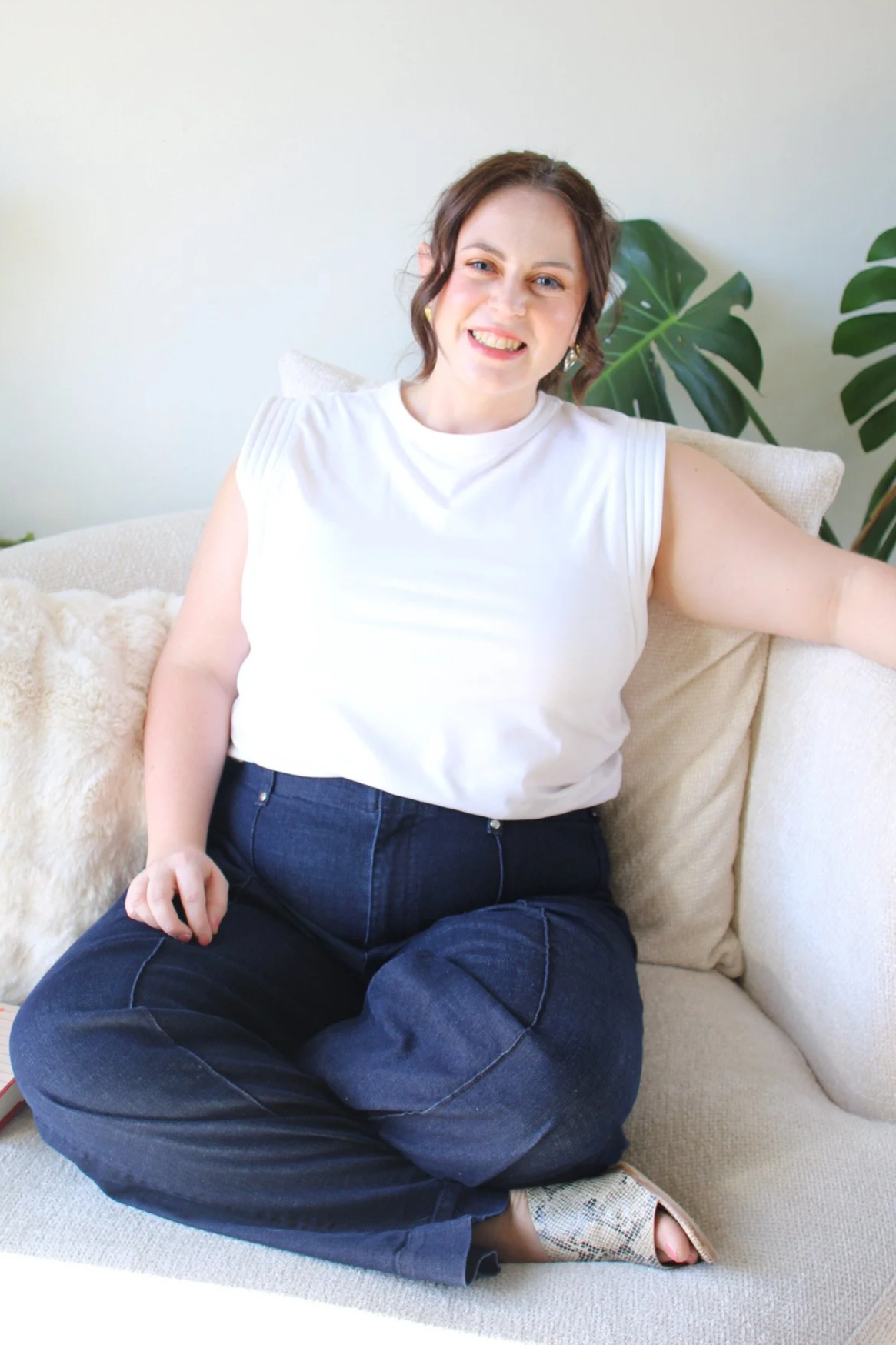 Aubrey Richardson, licensed professional counselor and founder of Sage Holistic Counseling,  therapist for therapists in Texas, sitting on a couch in a bright office space, specializing in burnout and people-pleasing recovery