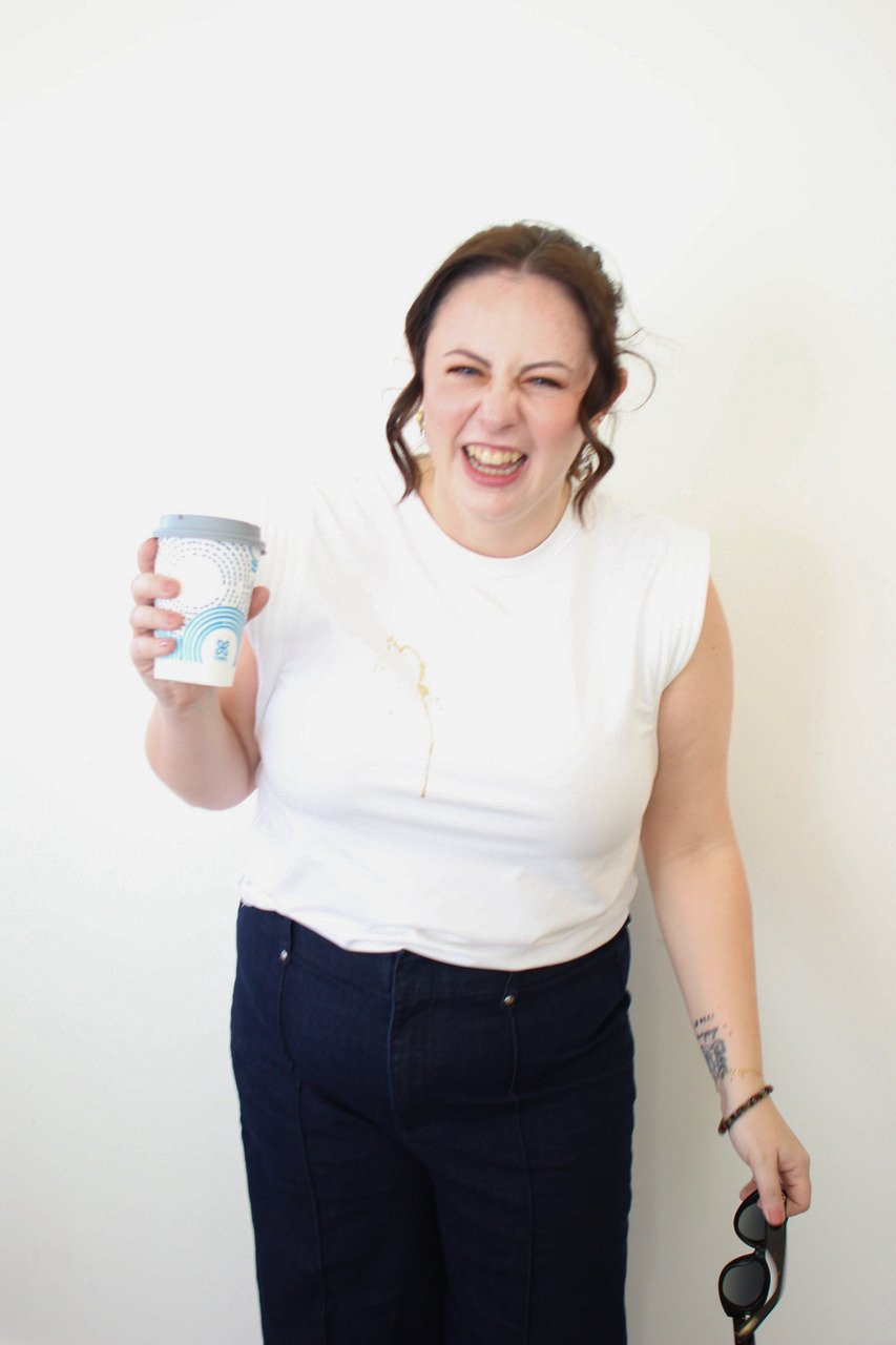 Woman laughing while holding spilled coffee representing burnout, overwhelm, and pressure in high achieving people pleasers seeking therapy in Texas