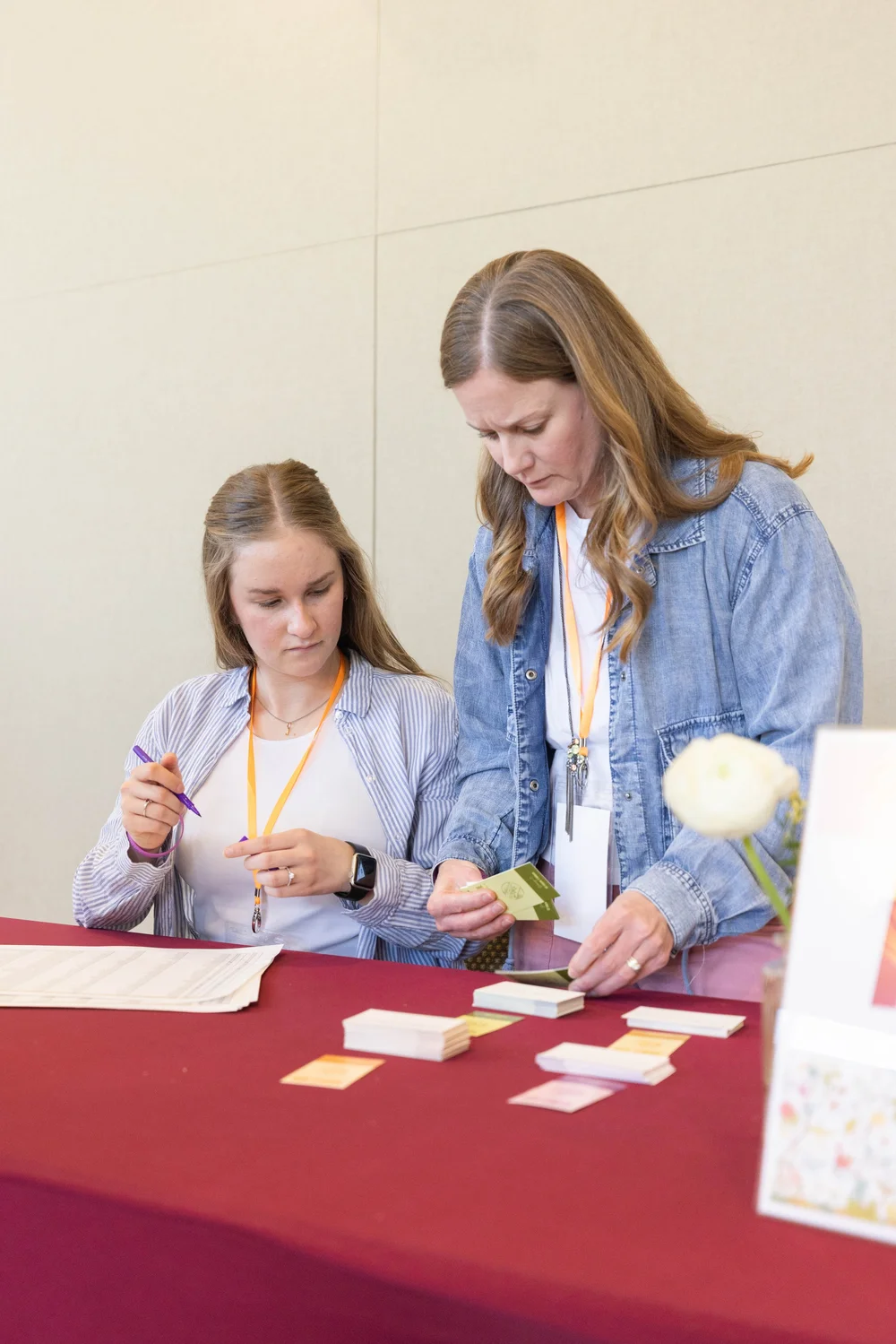 Two volunteers wearing MORE lanyards sort name cards behind the registration table.