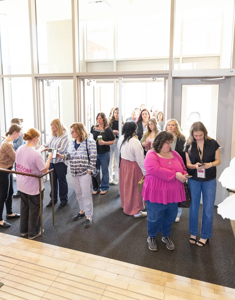 Women queue through the lobby doors as a volunteer manages the entry line at check-in.