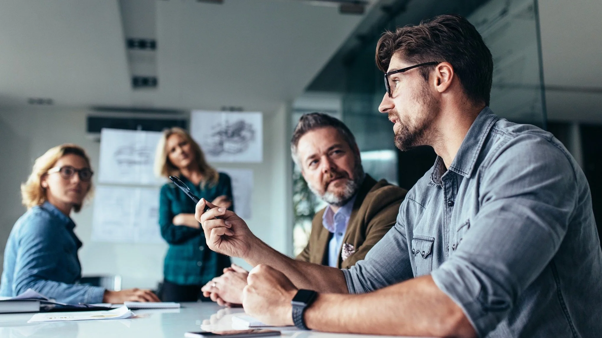 Four professionals having a discussion during a meeting in a modern office.