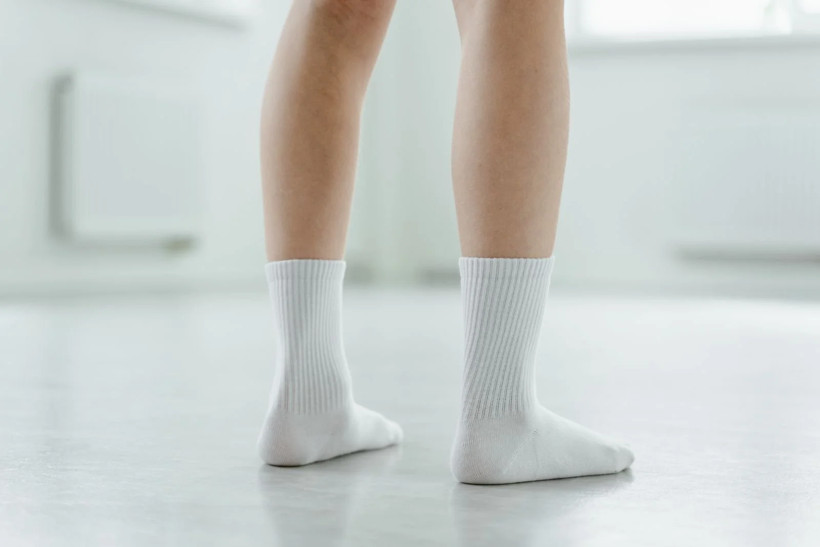 Piernas con calcetines blancos de algodón sobre piso claro
