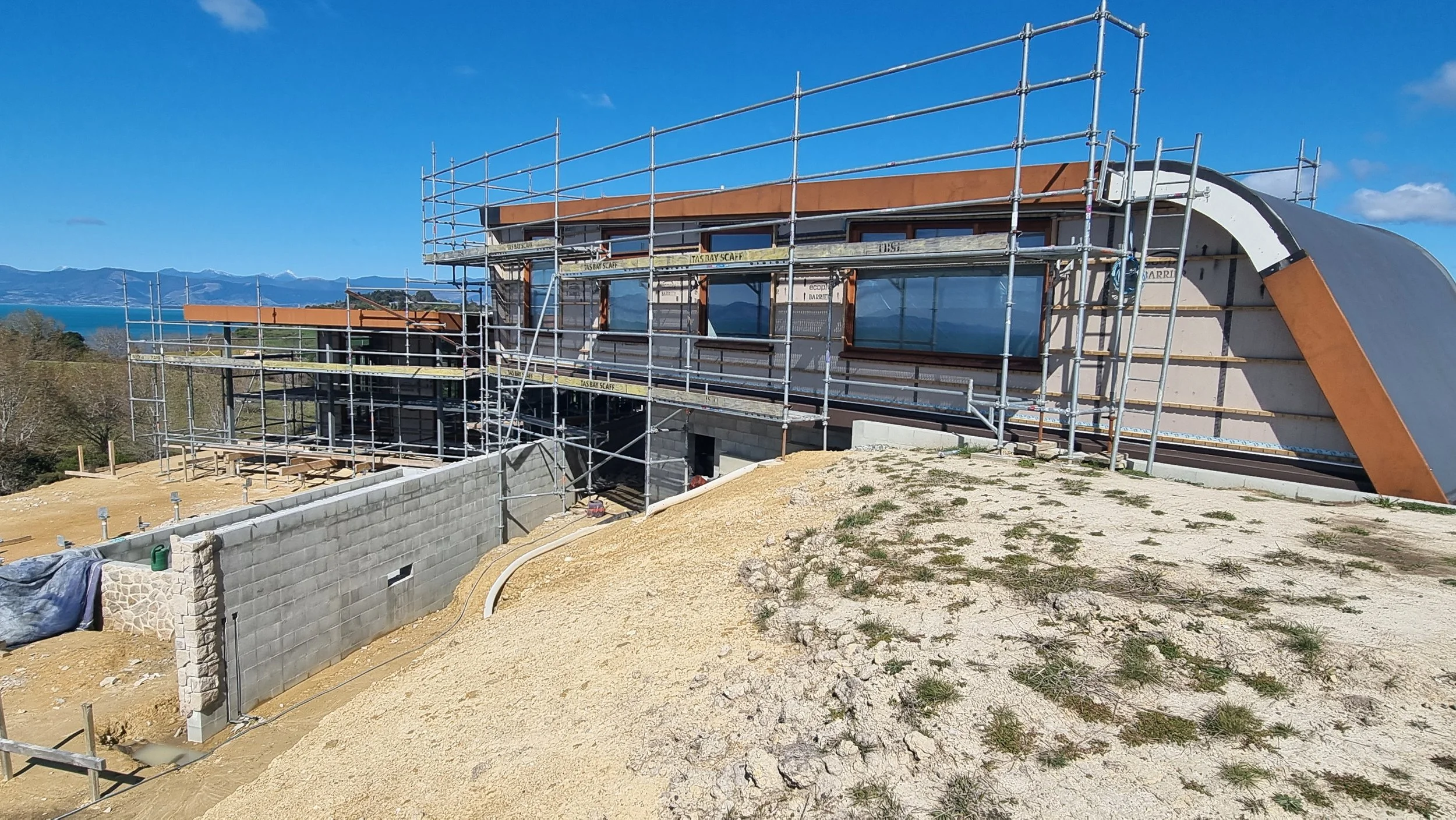 View of Northwest facade of new home in Tasman, scaffolding up, windows in designed by Waka Group Architecture