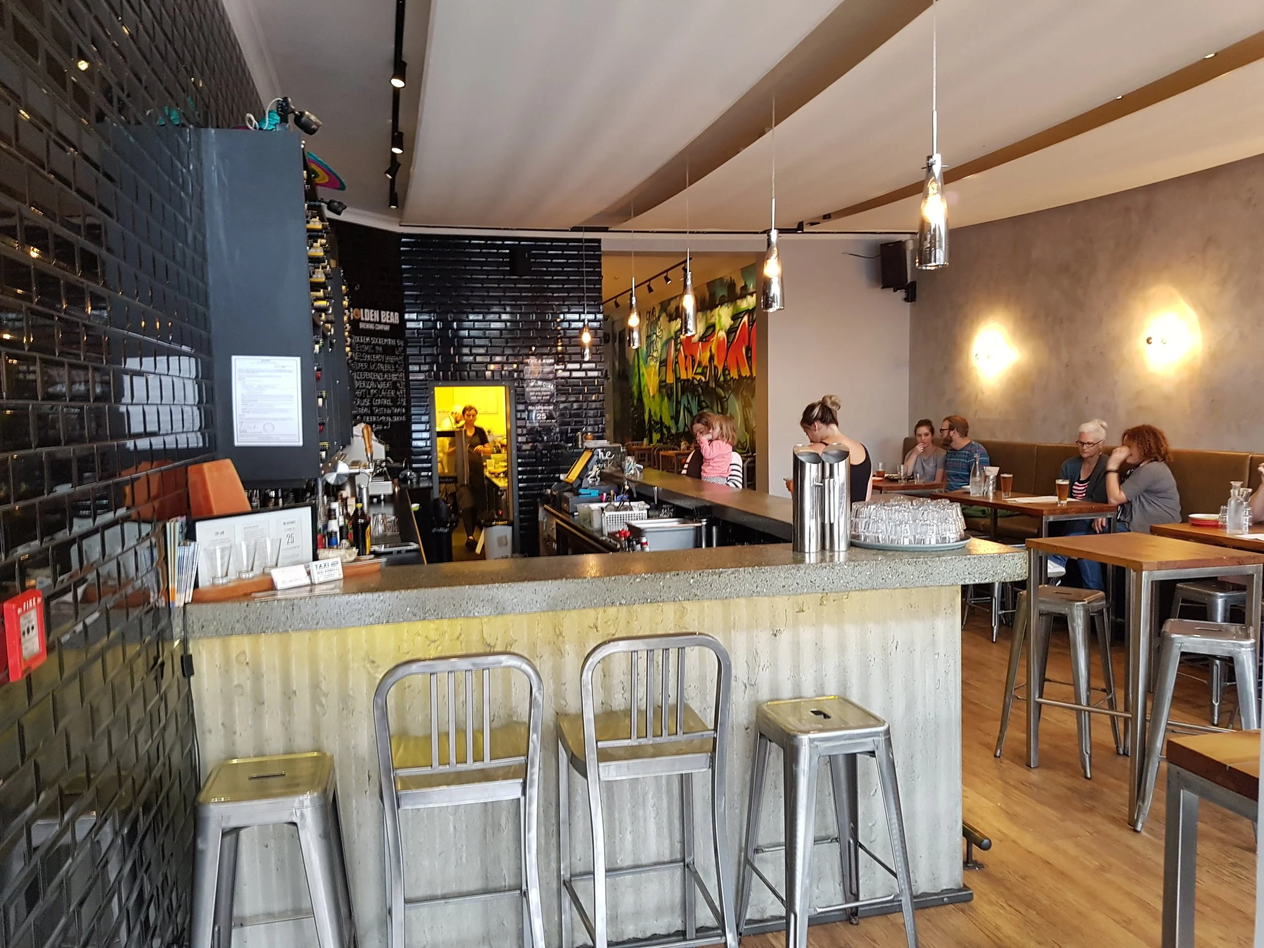 Bar area in restaurant refurbishment - black stacked brick for wall lining, corrugate look under bar top, stone bar top