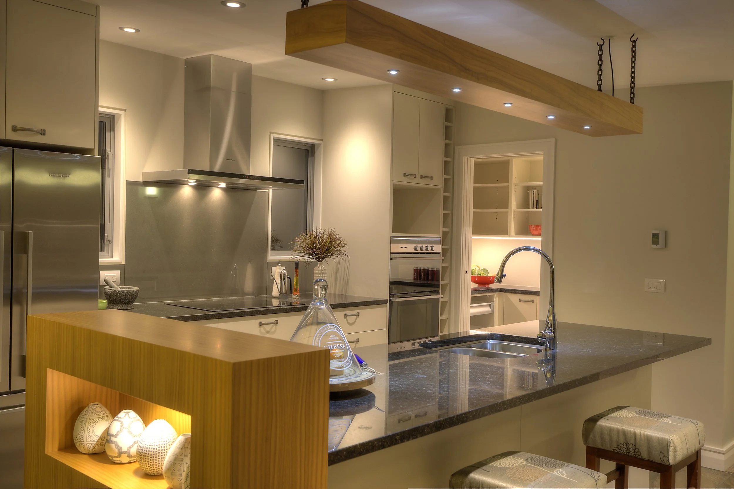 Kitchen between gable ends, large wooden hanging lighting feature over granite bench top designed by Architect Keni-Duke Hetet