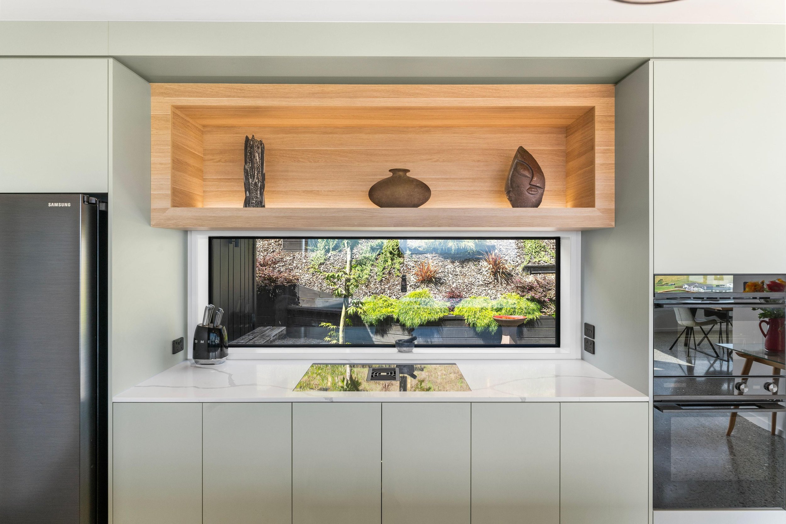 View out kitchen window, bench, bespoke joinery piece above - shelving