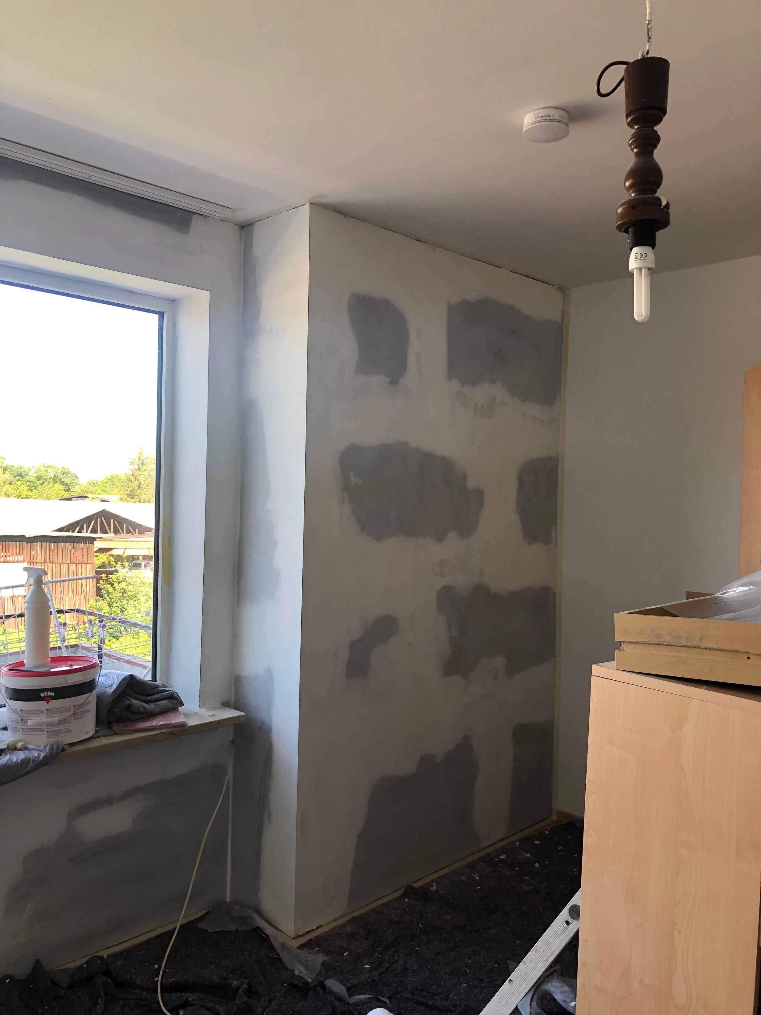 Innenraum eines Zimmers während der Renovierung mit unvollendeter Wand und offenem Fenster