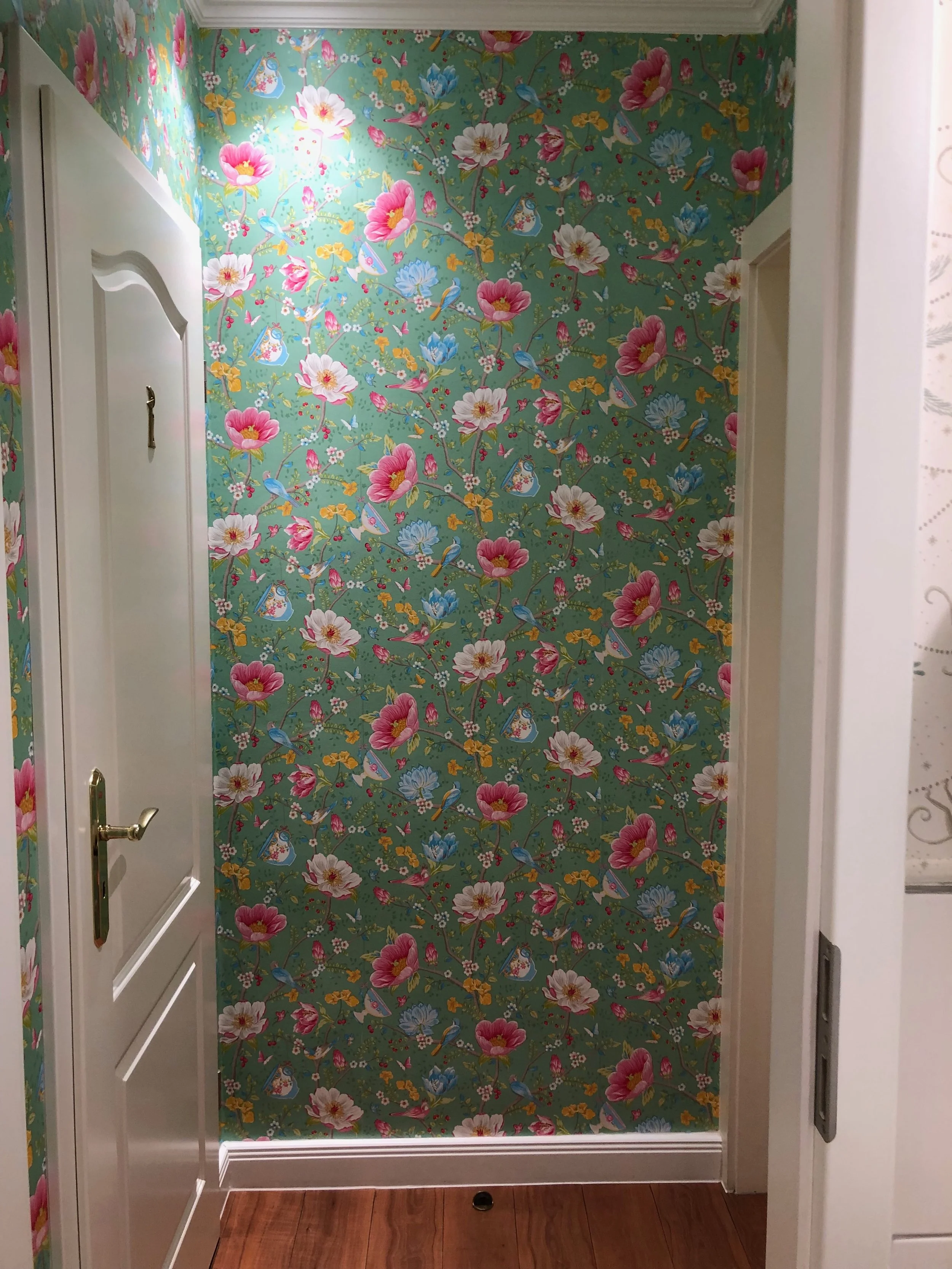 Innere Wand in einem Flur mit bunter, floraler Tapete mit Vögeln und Blumen.