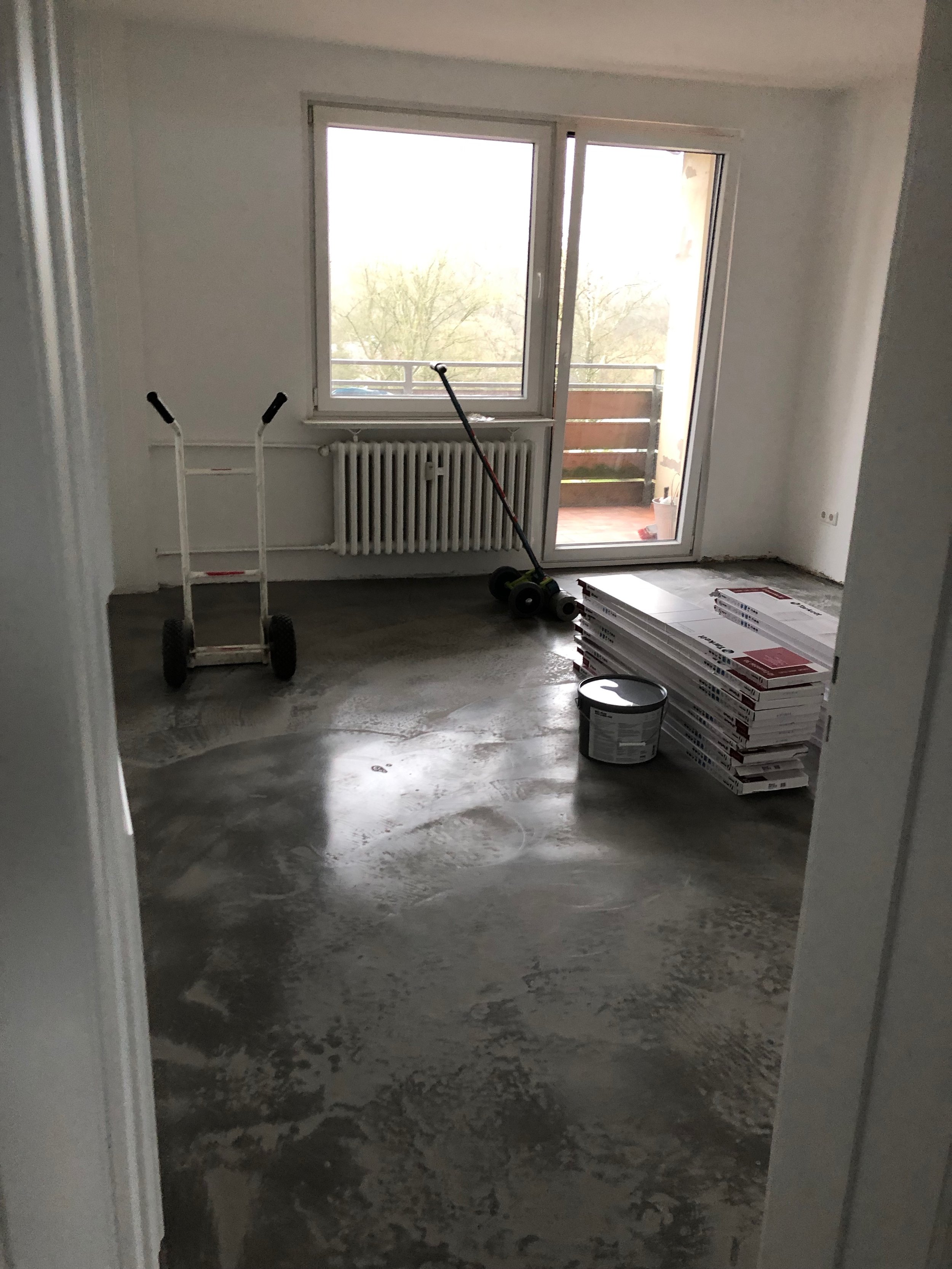 Ein leerer Raum in einem Haus, in dem gerade Renovierungsarbeiten durchgeführt werden, mit Baumaterialien und Werkzeugen auf dem Boden.