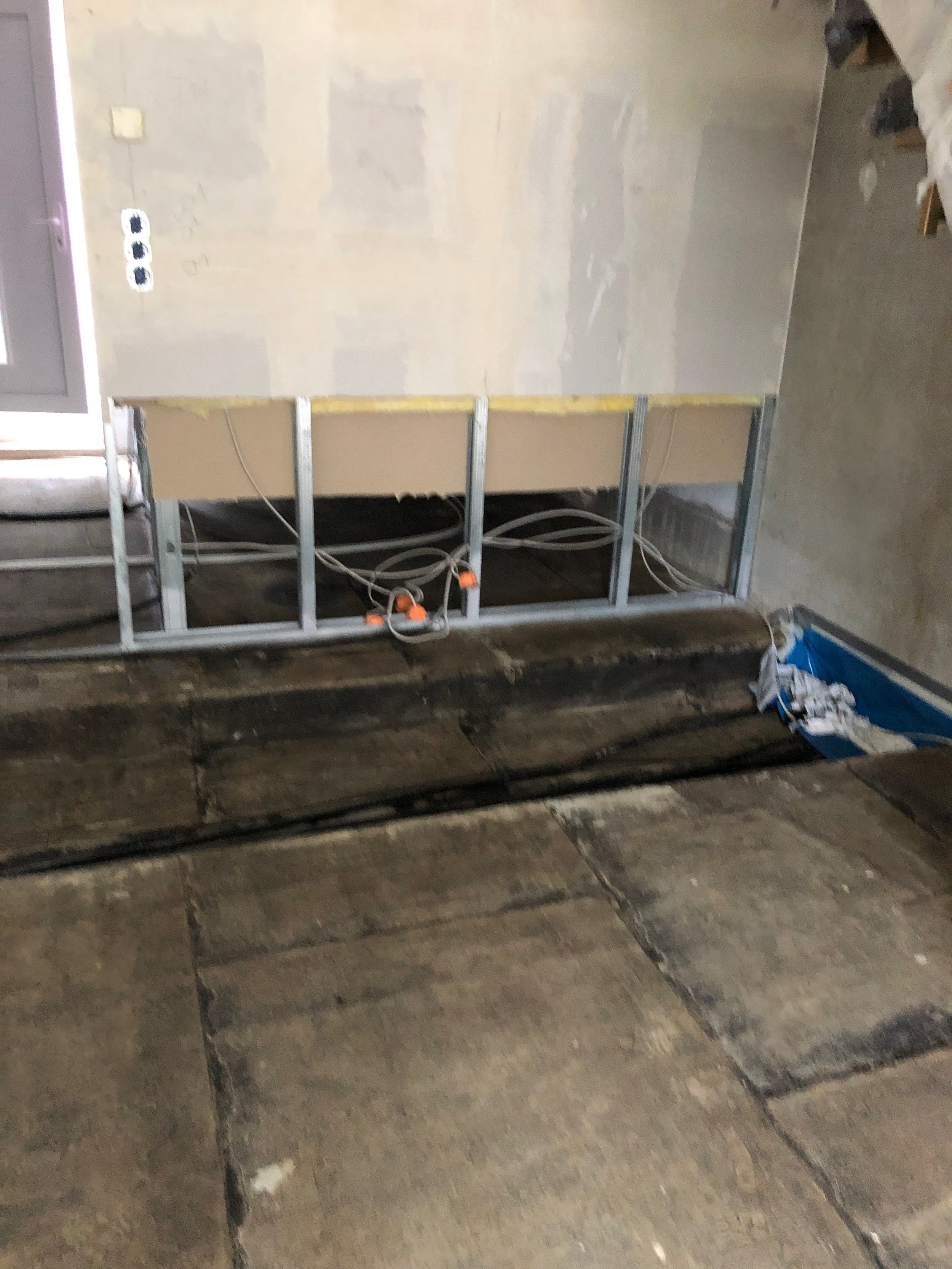 Innenraum eines Raums im Bau: unvollständige Wand mit sichtbarer Elektrik und Bodenplatten