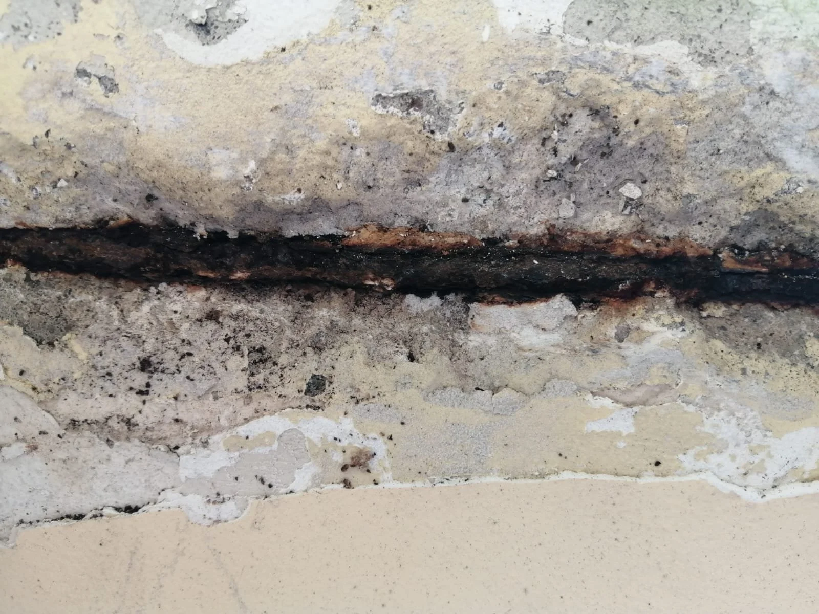 Riss im Mauerwerk mit sichtbarer Korrosion und Ablagerungen