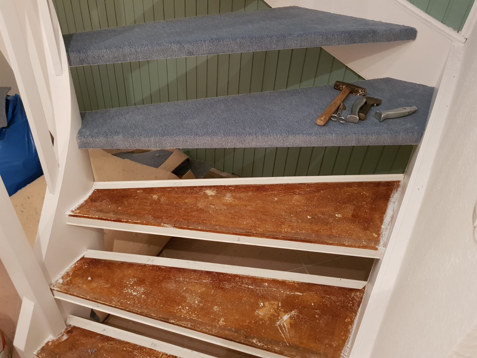 Bau- oder Renovierungsarbeit an einem Treppenabsatz, mit Werkzeugen wie Hammer und Zangen auf der Treppe.