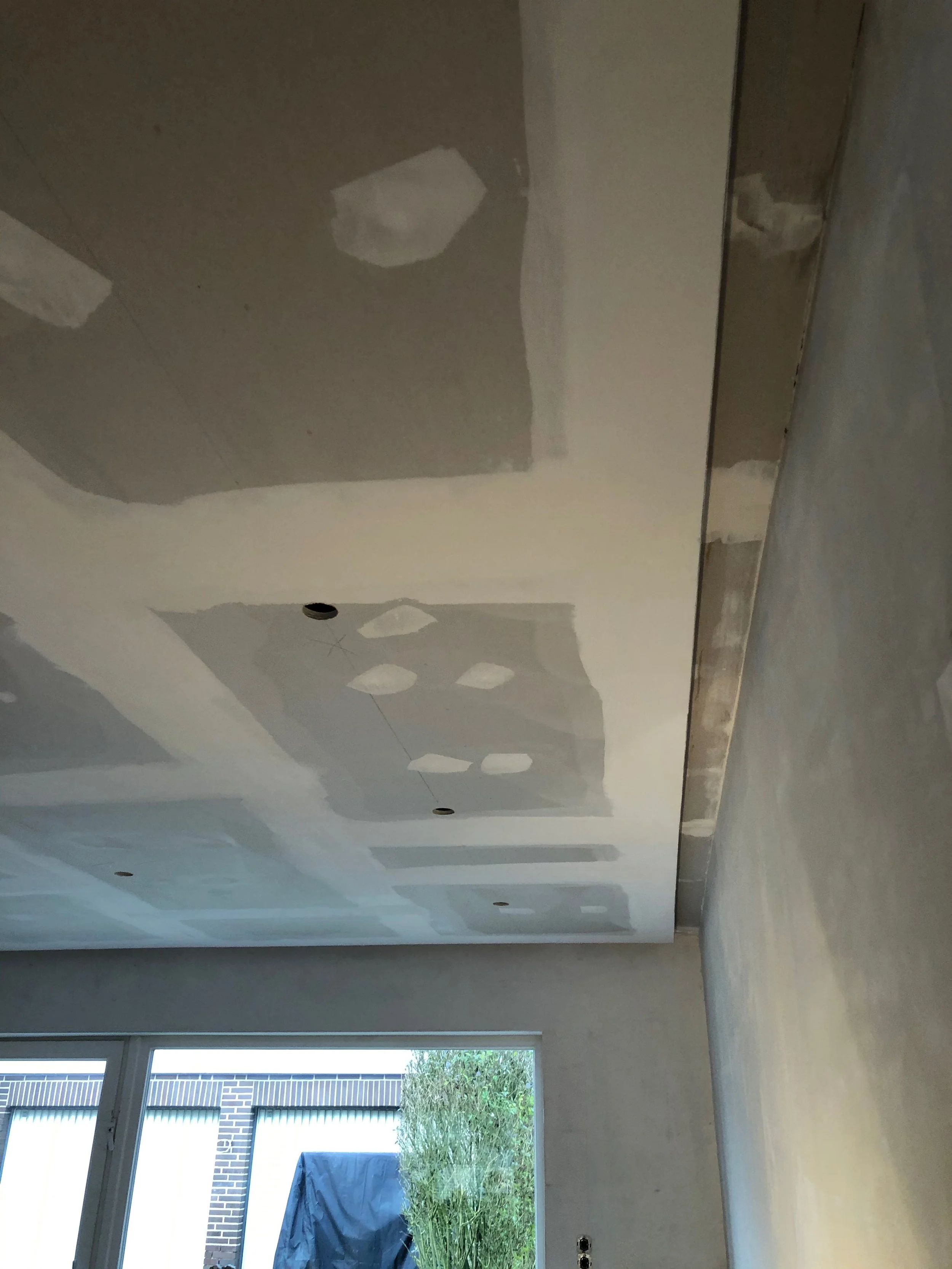 Decke eines Raums mit vorläufig ausgestatteten Trockenbau-Deckplatten, die noch verspachtelt werden müssen.