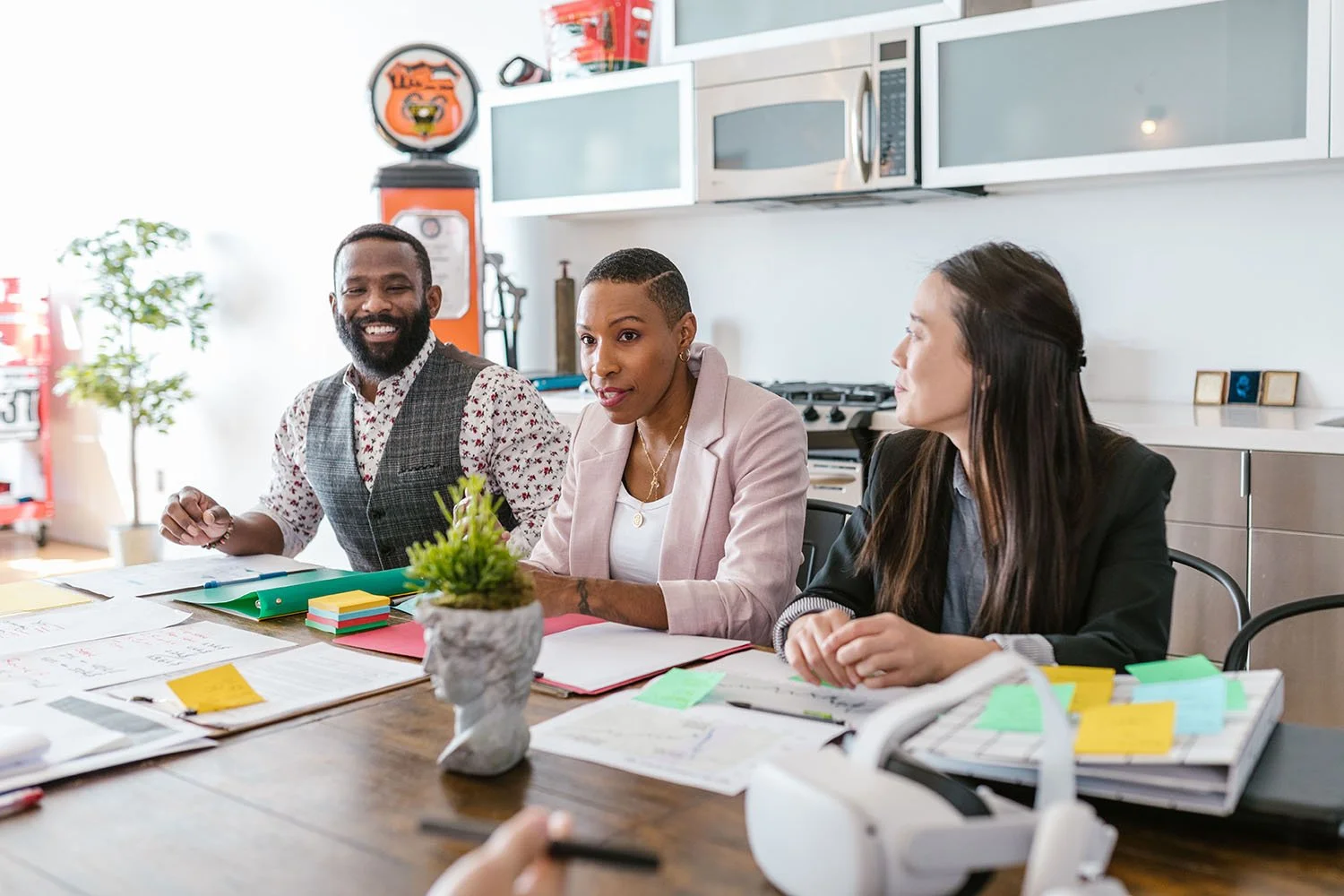 three members of nonprofit leadership team sitting at conference table discussing need for strategic planning consulting services