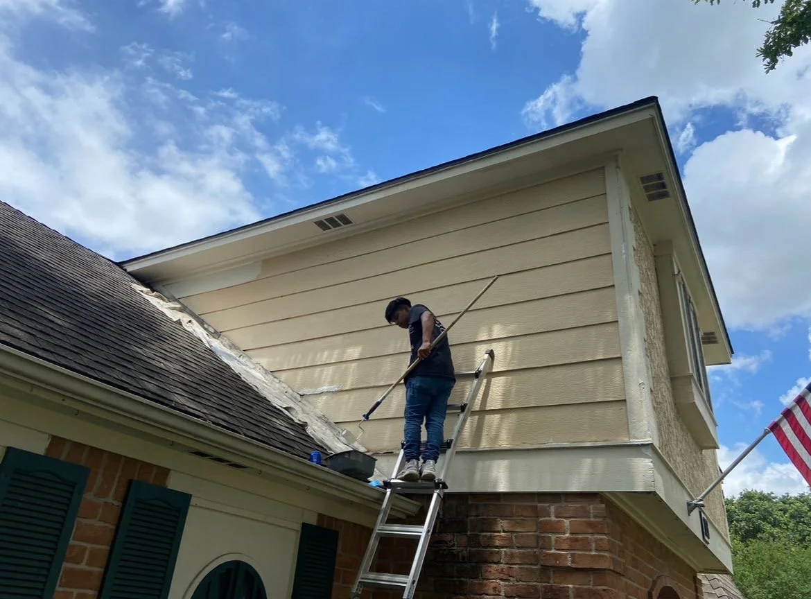 Person on ladder painting house exterior