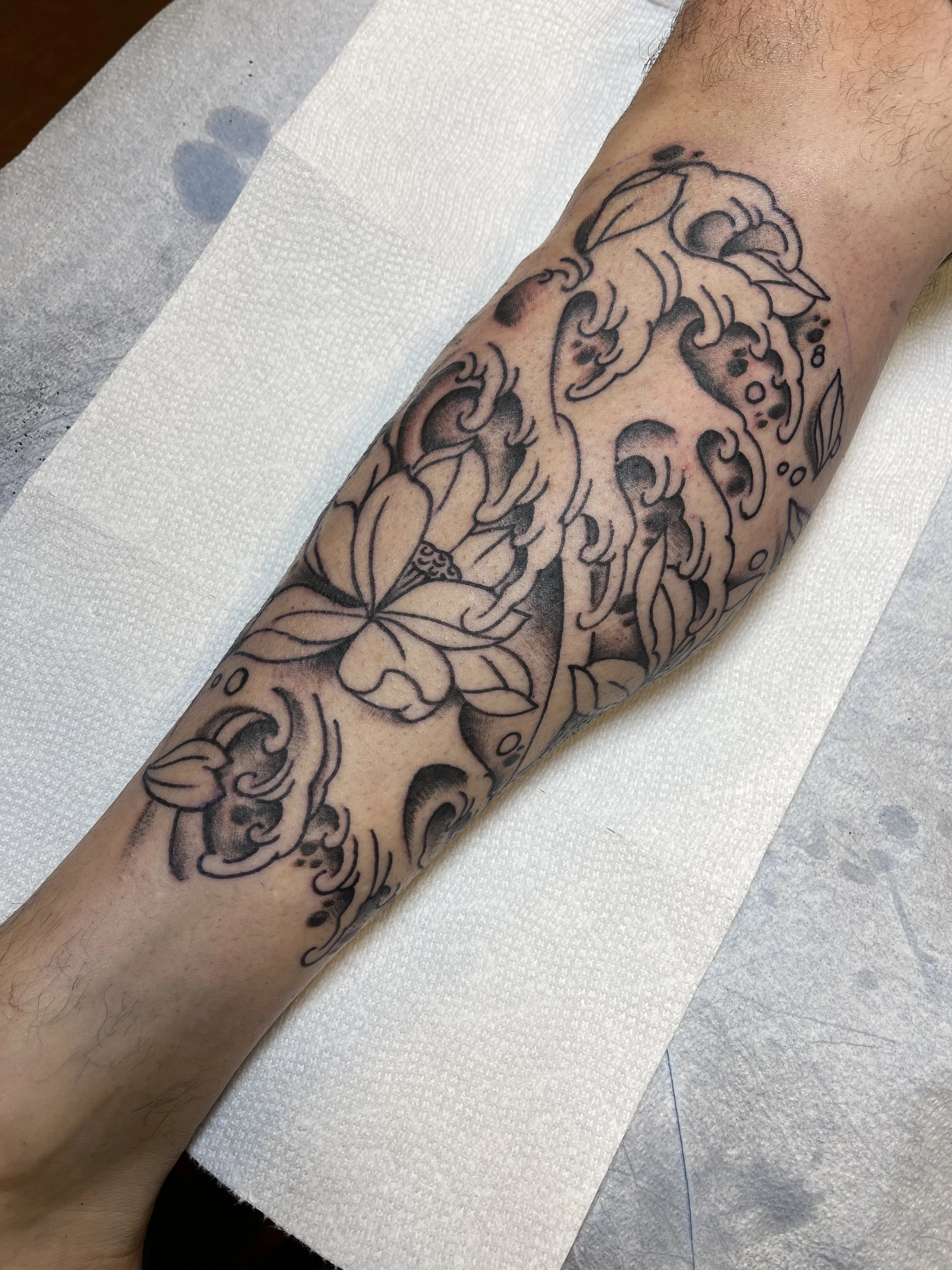 Japanese wave and flower tattoo on the leg by Electric Lotus Tattoo in NYC