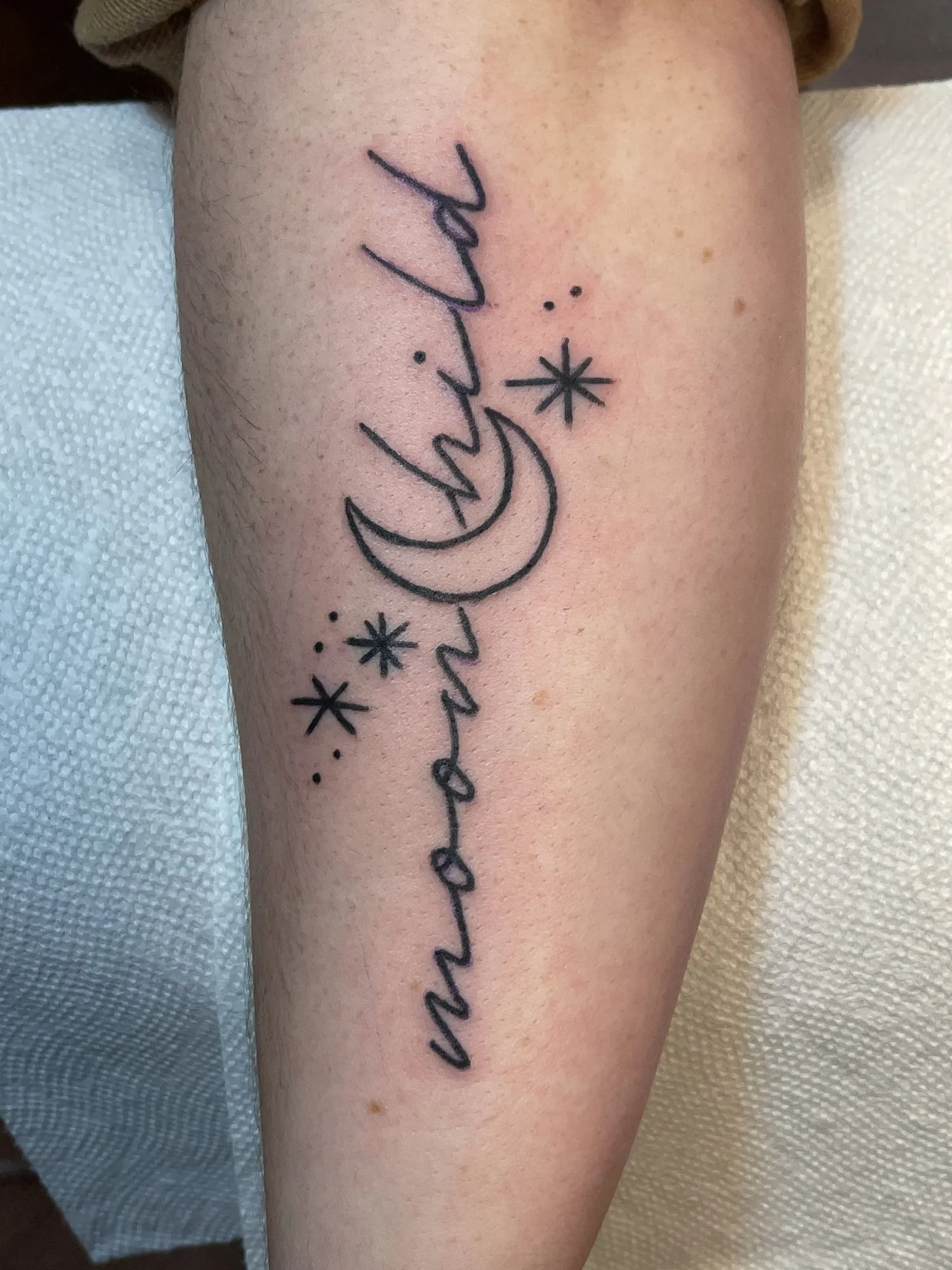 Fine line script tattoo reading moonchild on a calf.jpg