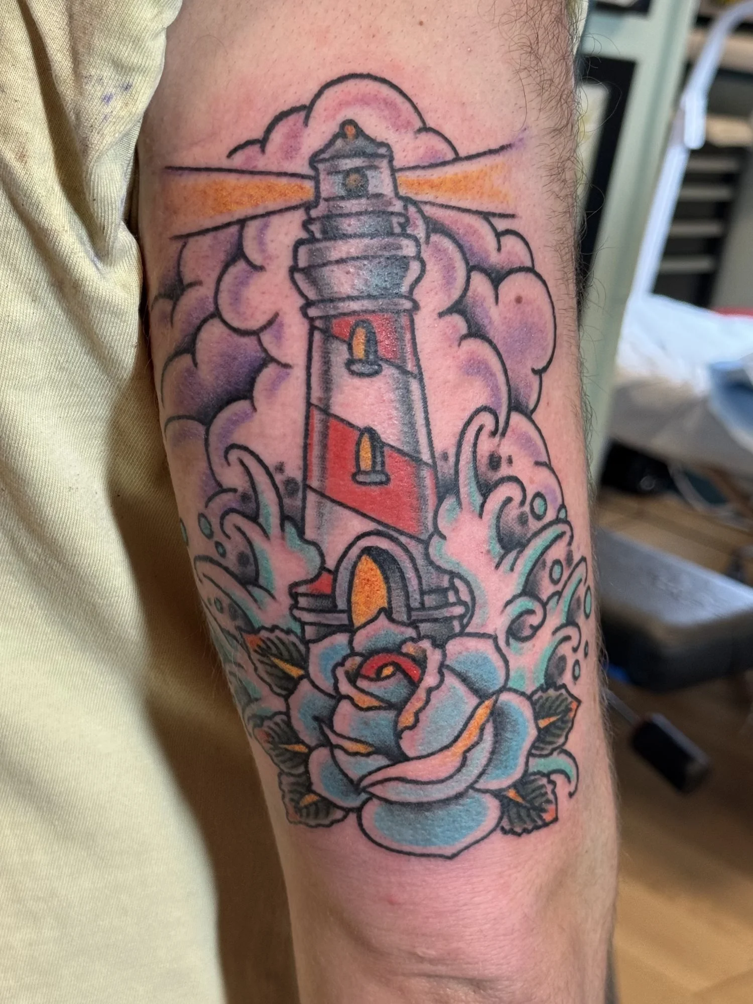 Traditional lighthouse and roses tattoo on an arm.jpg