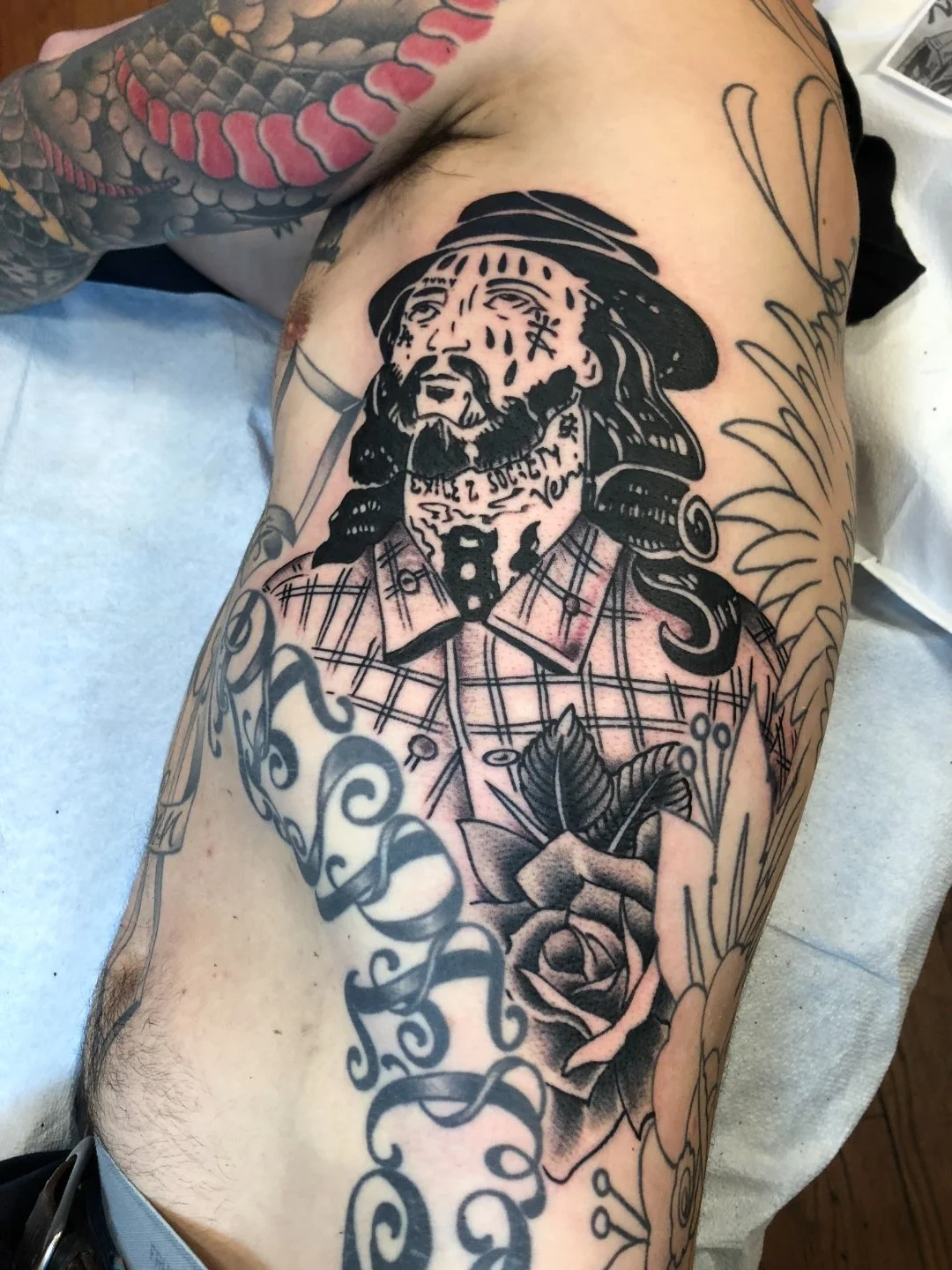Black and grey bearded man tattoo with rose on the ribs by Electric Lotus Tattoo in NYC