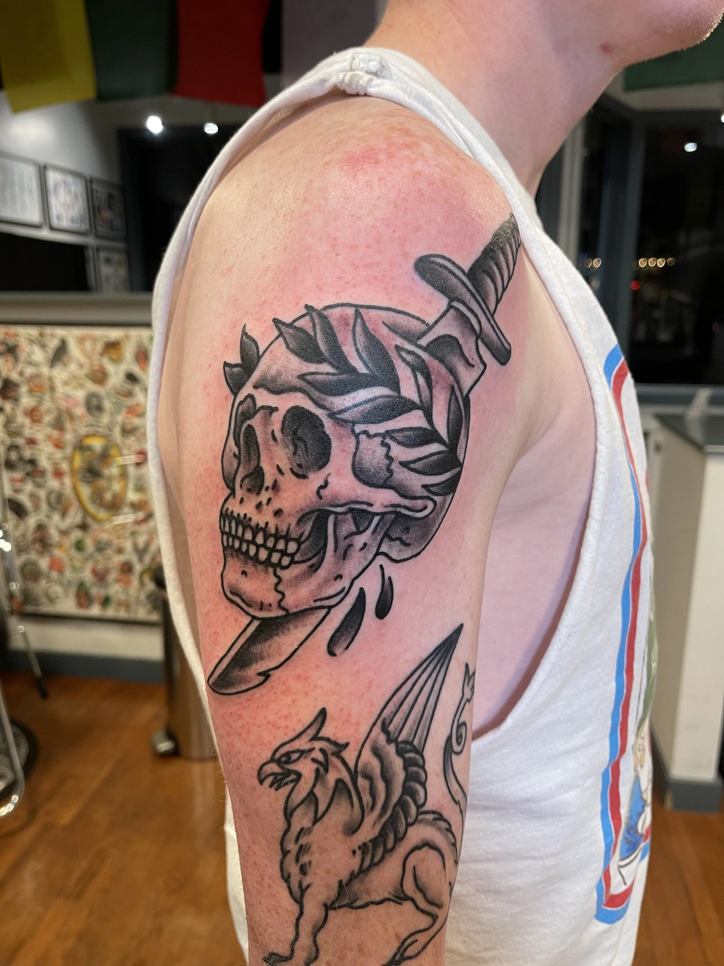 Black and grey skull and dagger tattoo with laurel leaves by Electric Lotus Tattoo in NYC