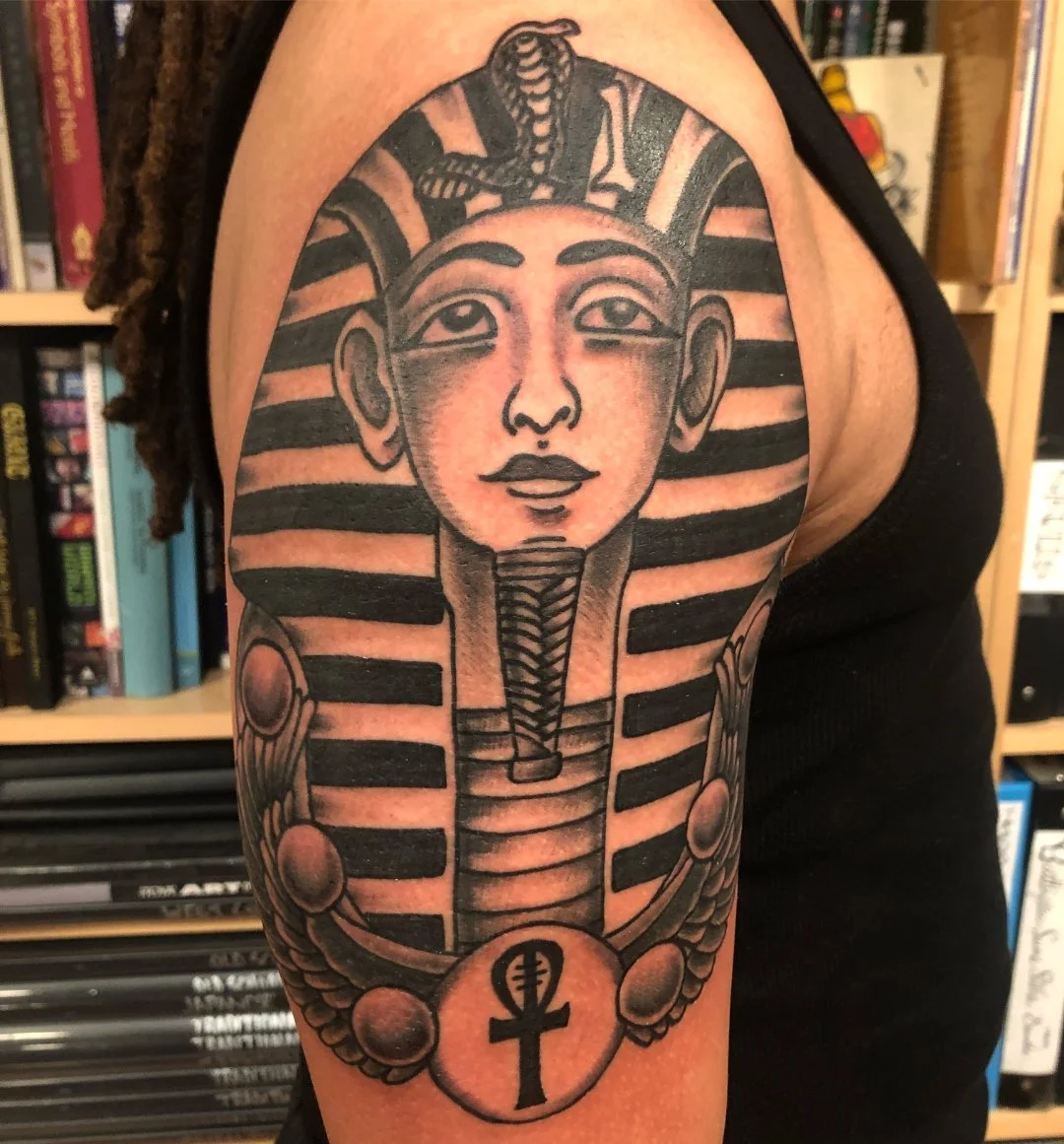 Black and grey Egyptian pharaoh tattoo on the upper arm by Electric Lotus Tattoo in NYC